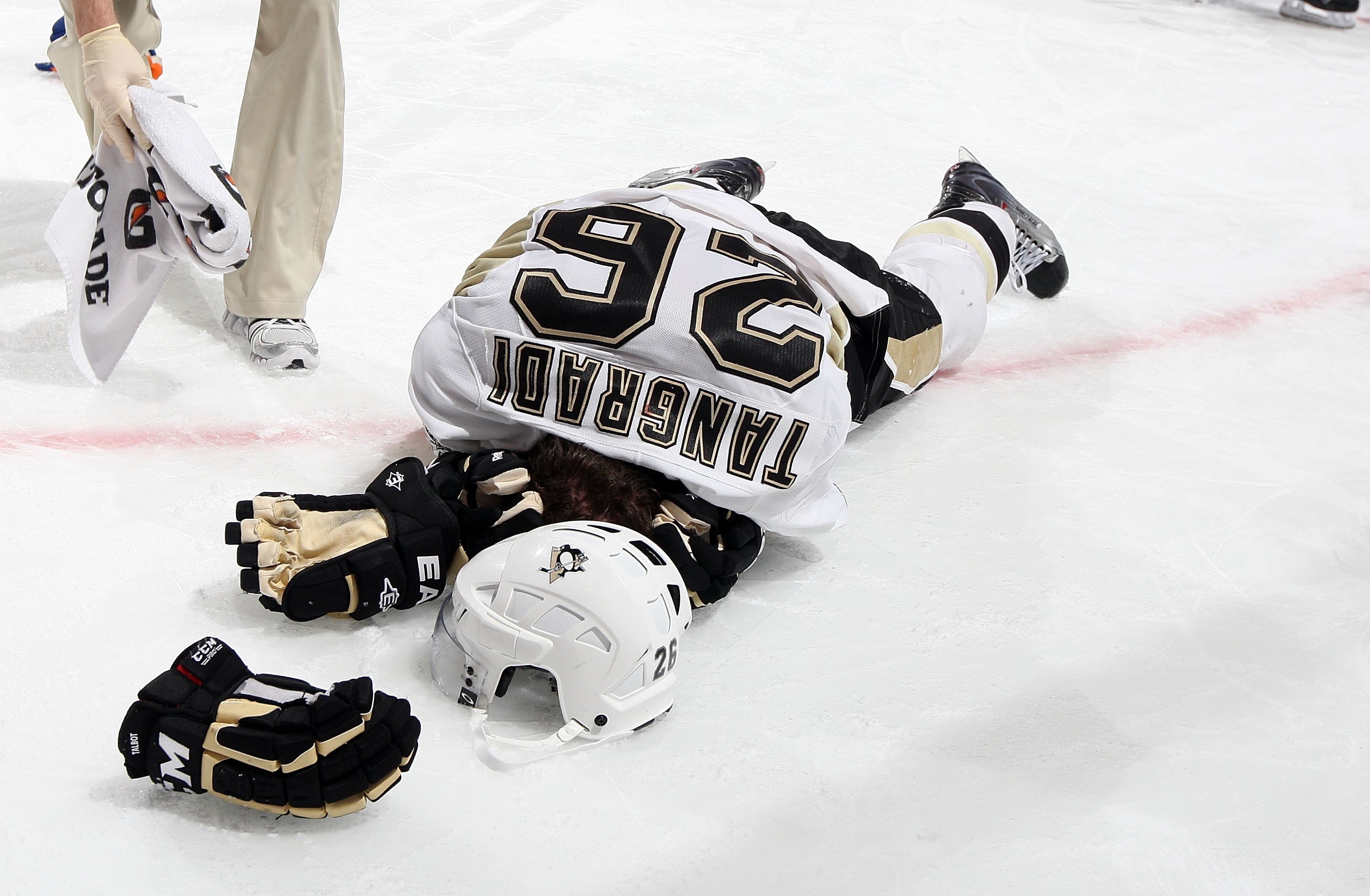UNIONDALE, NY - FEBRUARY 11:  Eric Tangradi #26 of the Pittsburgh Penguins lays on the ice after taking a hit to the head from Trevor Gillies (not pictured) of the New York Islanders on February 11, 2011 at Nassau Coliseum in Uniondale, New York. The Isle