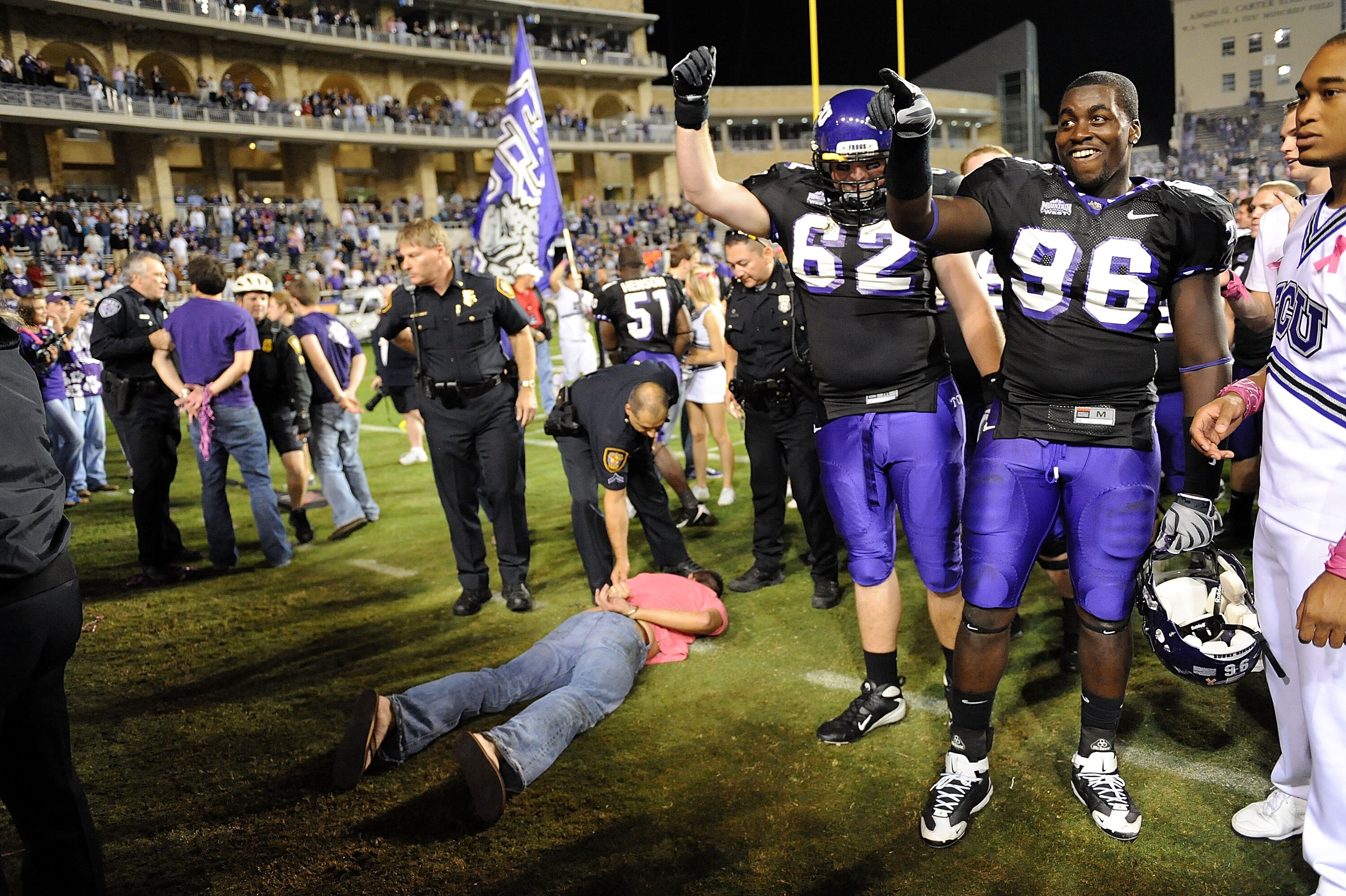 FORT WORTH, TX - OCTOBER 16:  Defensive end Wayne Daniels #96 and Jeff Olson #62 of the TCU Horned Frogs celebrate a win against the BYU Cougars as fans are detained by Fort Worth Police at Amon G. Carter Stadium on October 16, 2008 in Fort Worth, Texas.