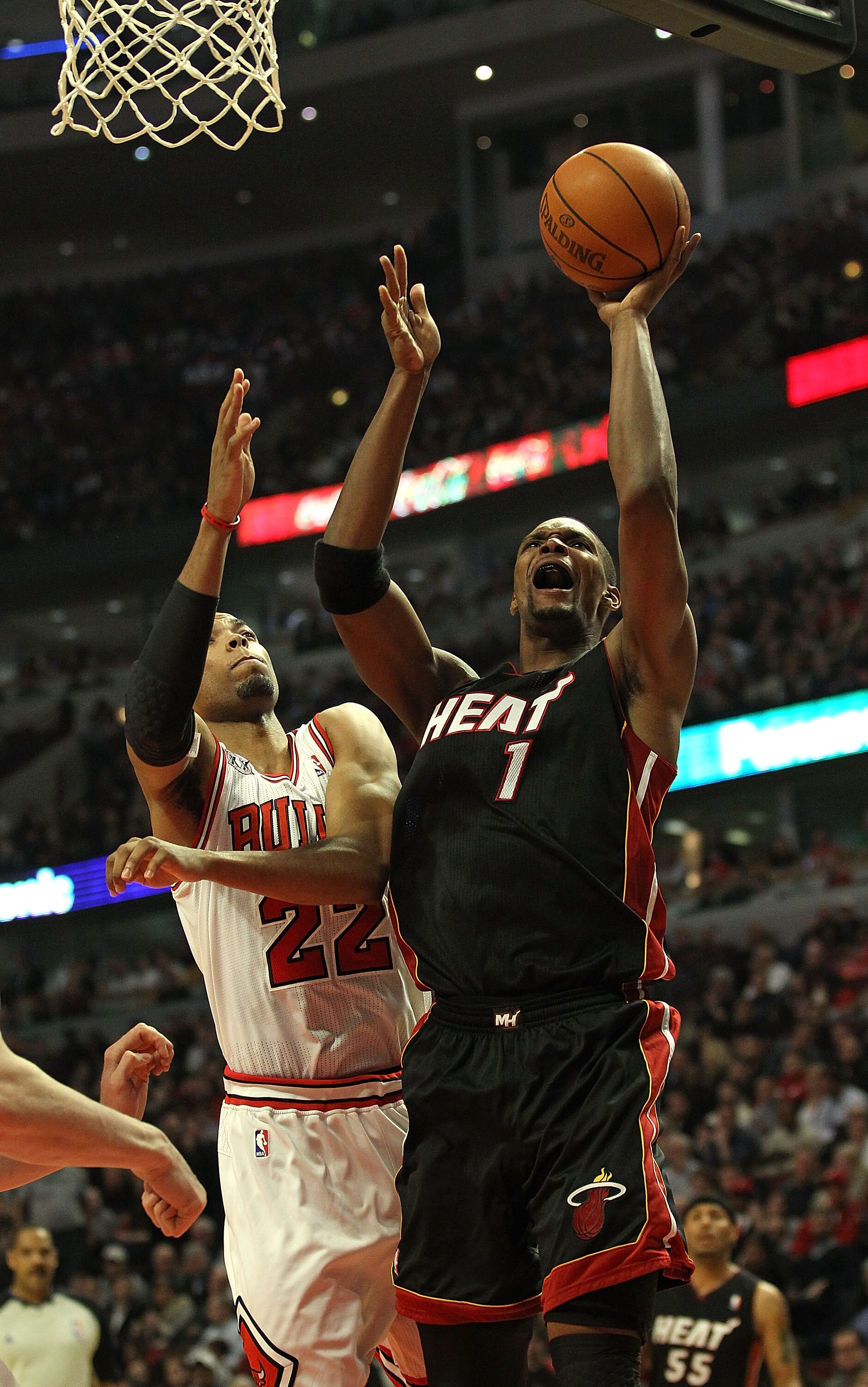 CHICAGO, IL - FEBRUARY 24: Chris Bosh #1 of the Miami Heat puts up a shot under pressure from Taj Gibson #22 of the Chicago Bulls at the United Center on February 24, 2011 in Chicago, Illinois. NOTE TO USER: User expressly acknowledges and agrees that, by