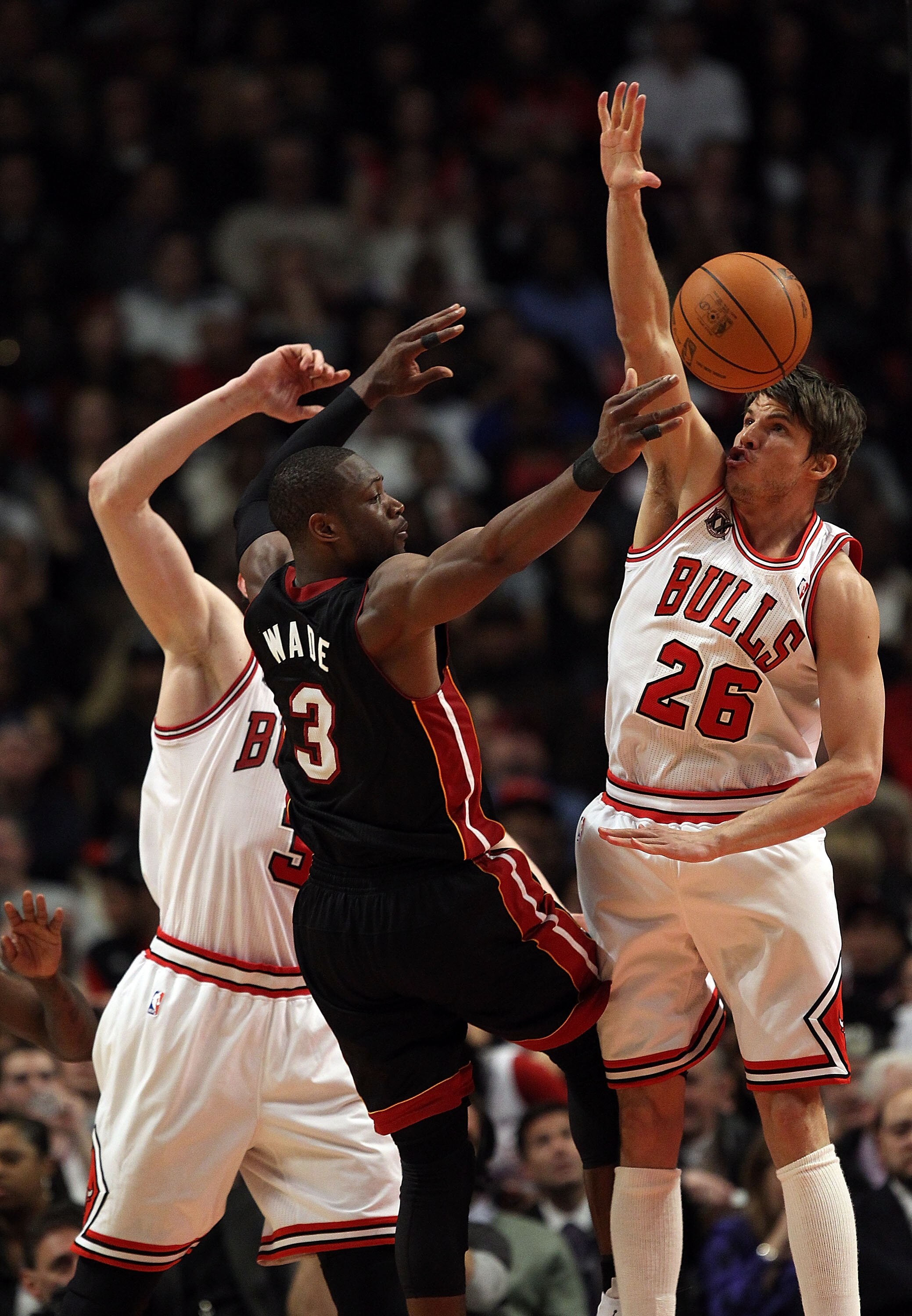 CHICAGO, IL - FEBRUARY 24: Dwyane Wade #3 of the Miami Heat passes the ball under pressure from Omer Asik #3 and Kyle Korver #26 of the Chicago Bulls at the United Center on February 24, 2011 in Chicago, Illinois. The Bulls defeated the Heat 93-89. NOTE T