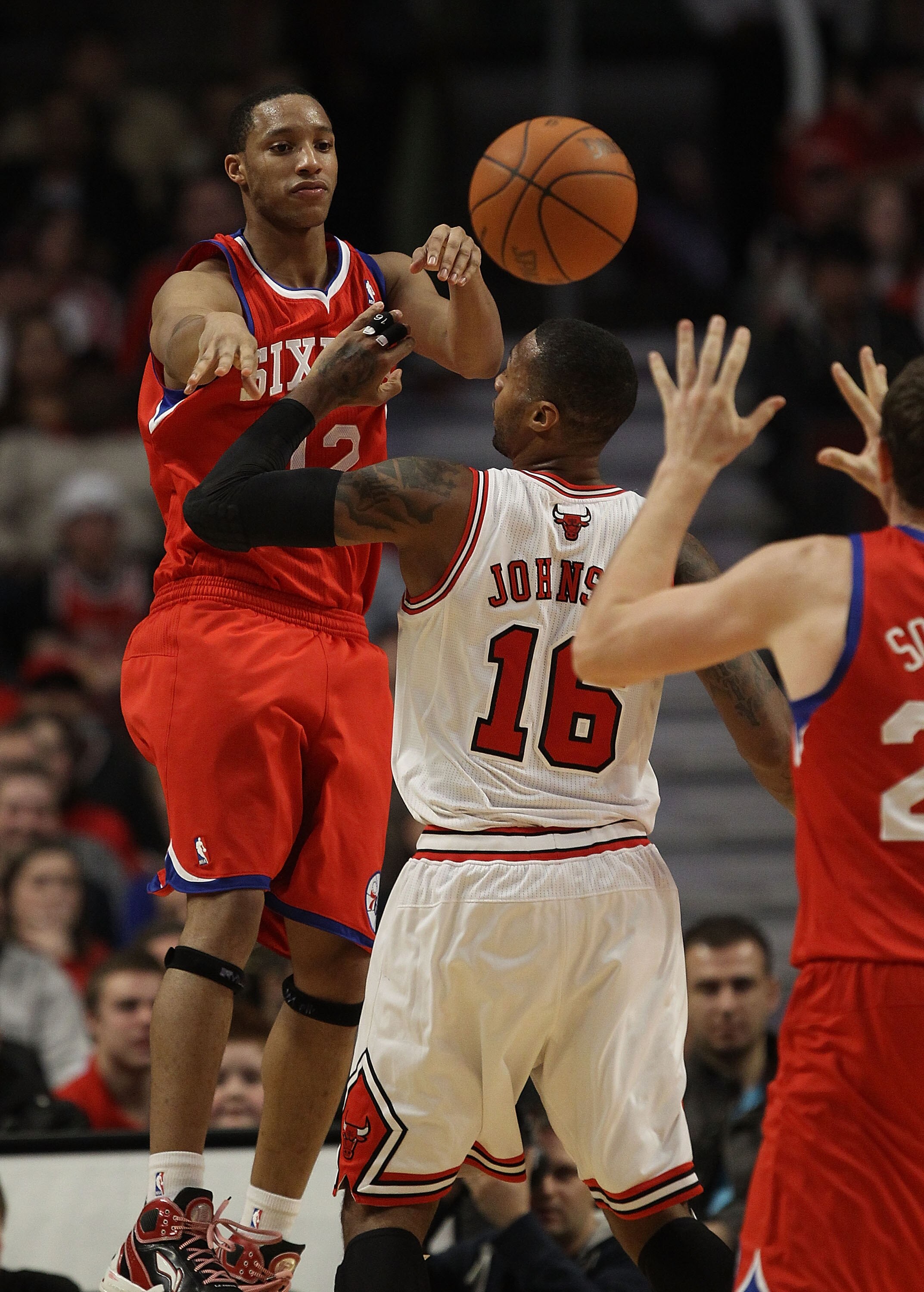 CHICAGO, IL - DECEMBER 21: Evan Turner #12 of the Philadelphia 76ers jumps to pass the ball over James Johnson #16 of the Chicago Bulls at the United Center on December 21, 2010 in Chicago, Illinois. The Bulls defeated the 76ers 121-76. NOTE TO USER: User