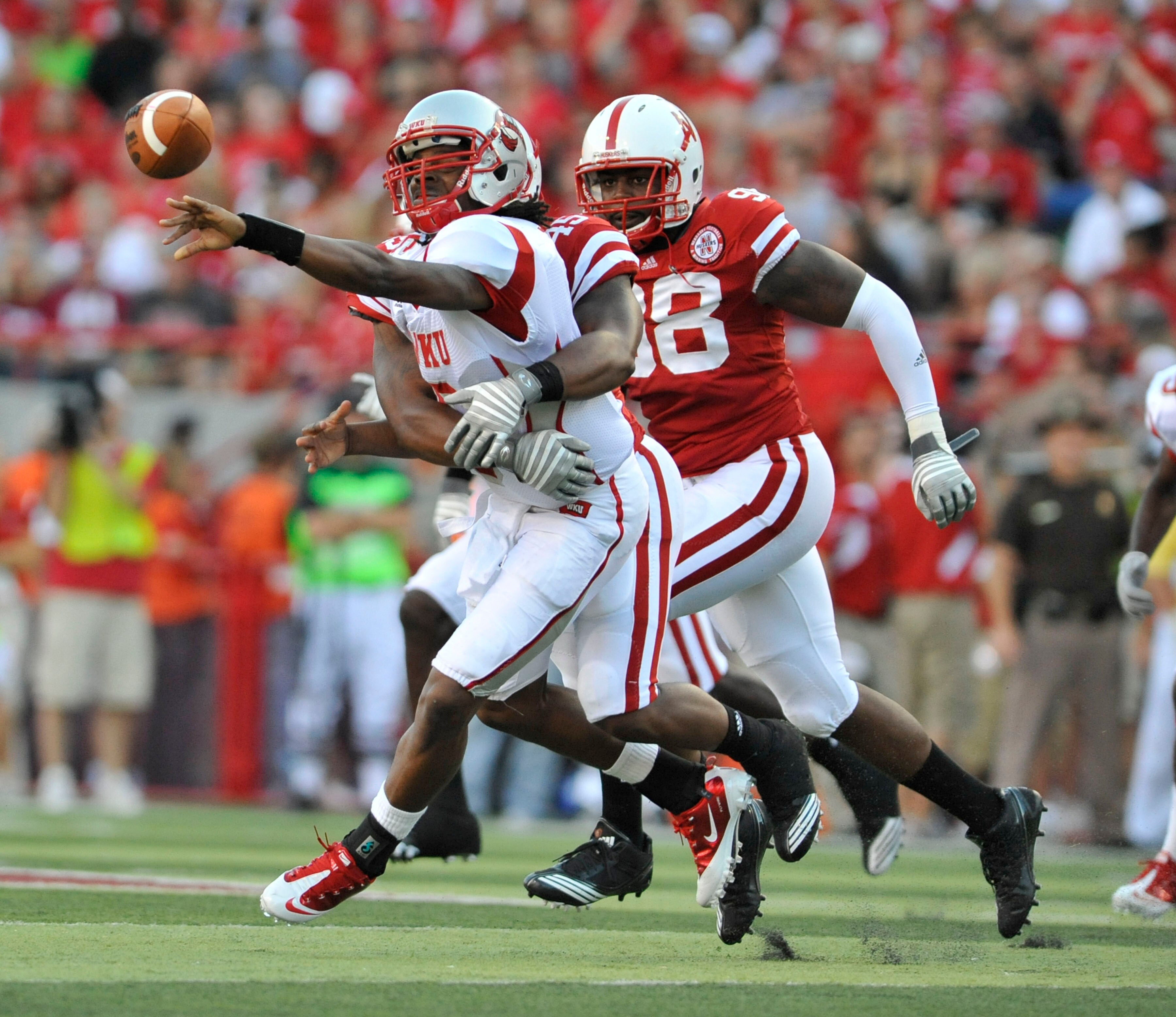 LINCOLN, NE - SEPTEMBER 04:  Kawaun Jakes #6 of the Western Kentucky Hilltoppers pitches the ball as he gets hit by Alonzo Whaley #45 of the Nebraska Cornhuskers during first half action of their game at Memorial Stadium on September 4, 2010 in Lincoln, N