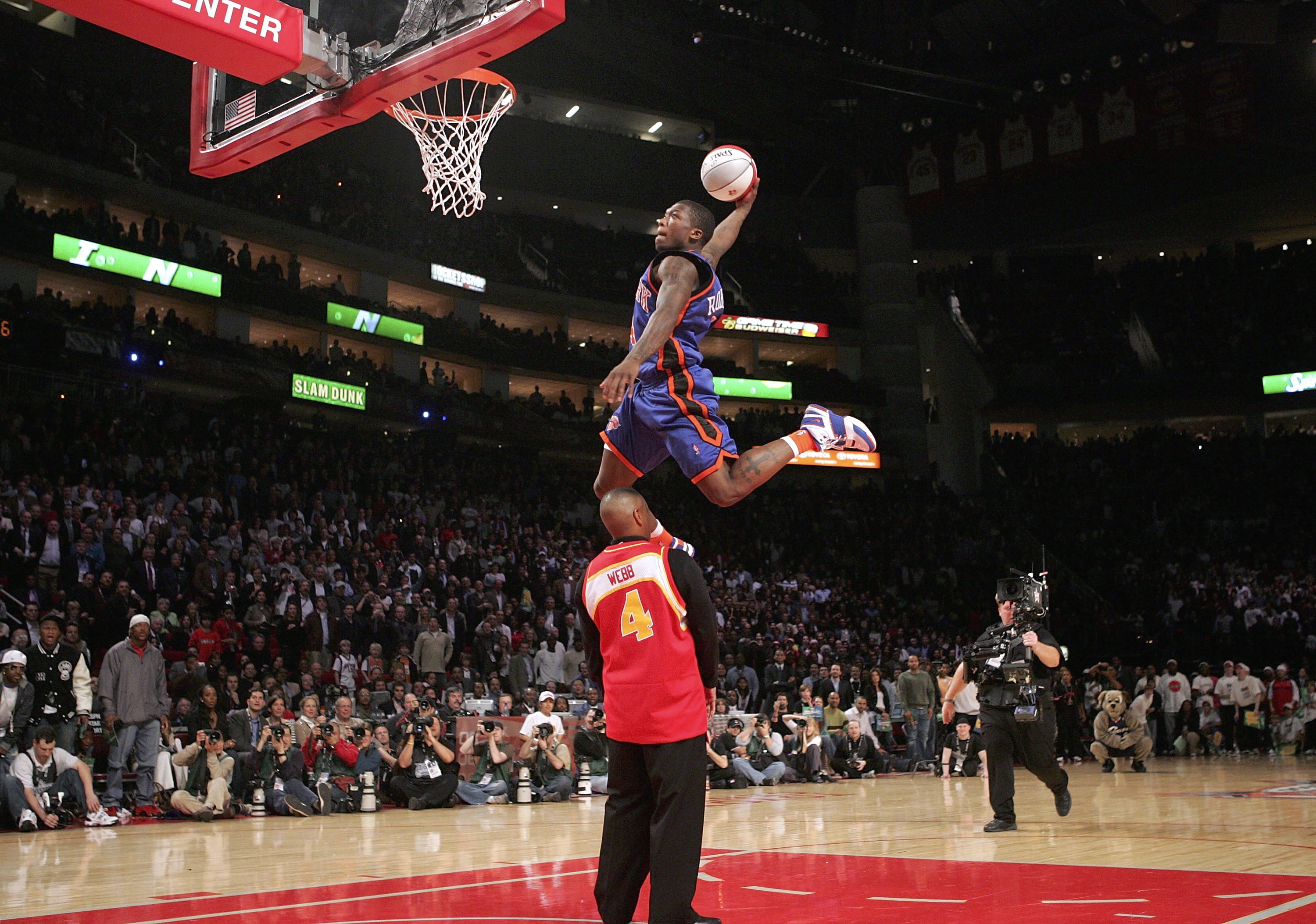 HOUSTON - FEBRUARY 18:  Nate Robinson #4 of the New York Knicks goes up for a dunk over former slam dunk champion Spud Webb in the Sprite Rising Stars Slam Dunk competition during NBA All-Star Weekend at the Toyota Center on February 18, 2006 in Houston,