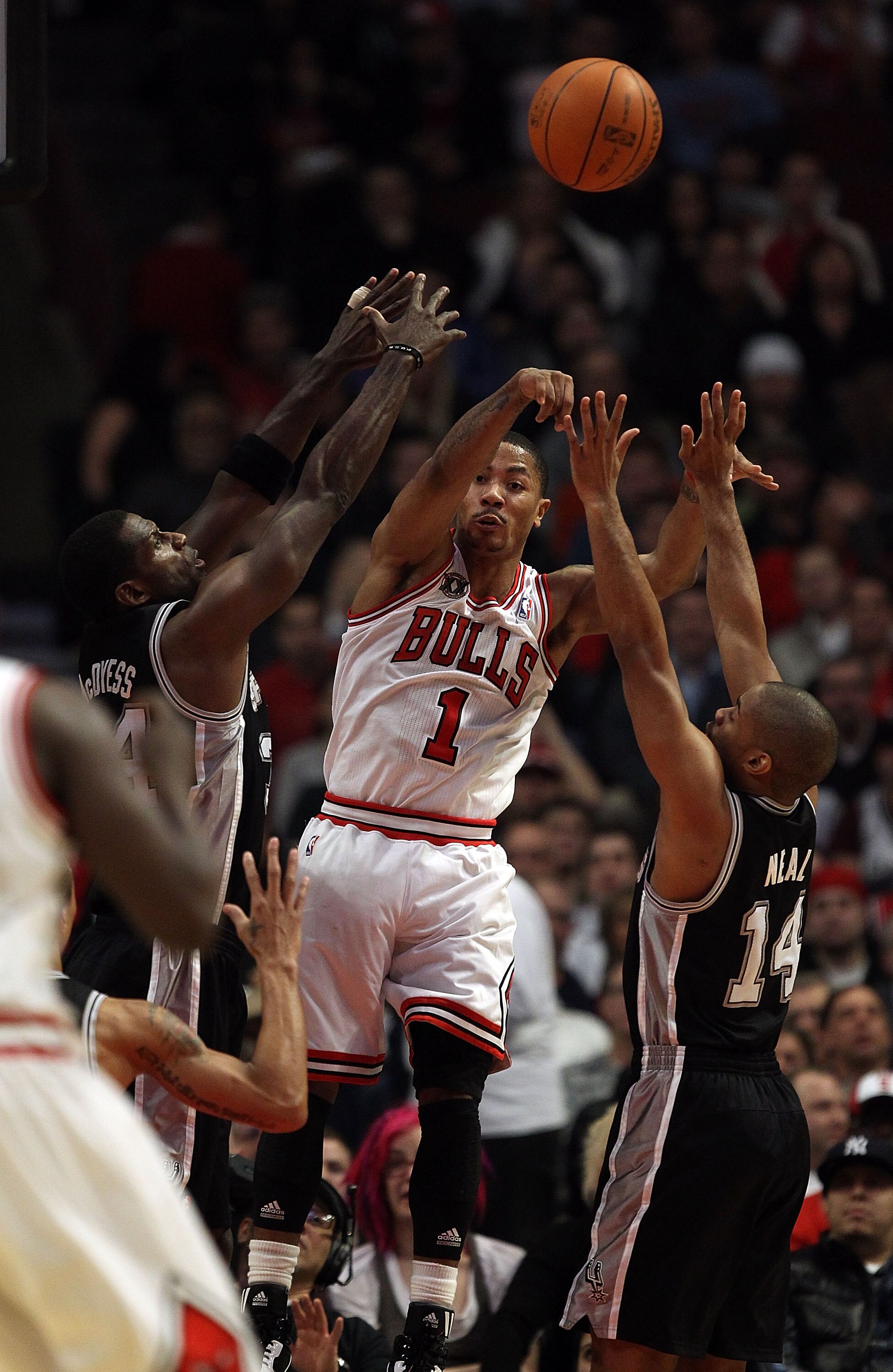 CHICAGO, IL - FEBRUARY 17: Derrick Rose #1 of the Chicago Bulls leaps to pass between Antonio McDyess #34 and Gary Neal #14 of the San Antonio Spurs at the United Center on February 17, 2011 in Chicago, Illinois. NOTE TO USER: User expressly acknowledges 