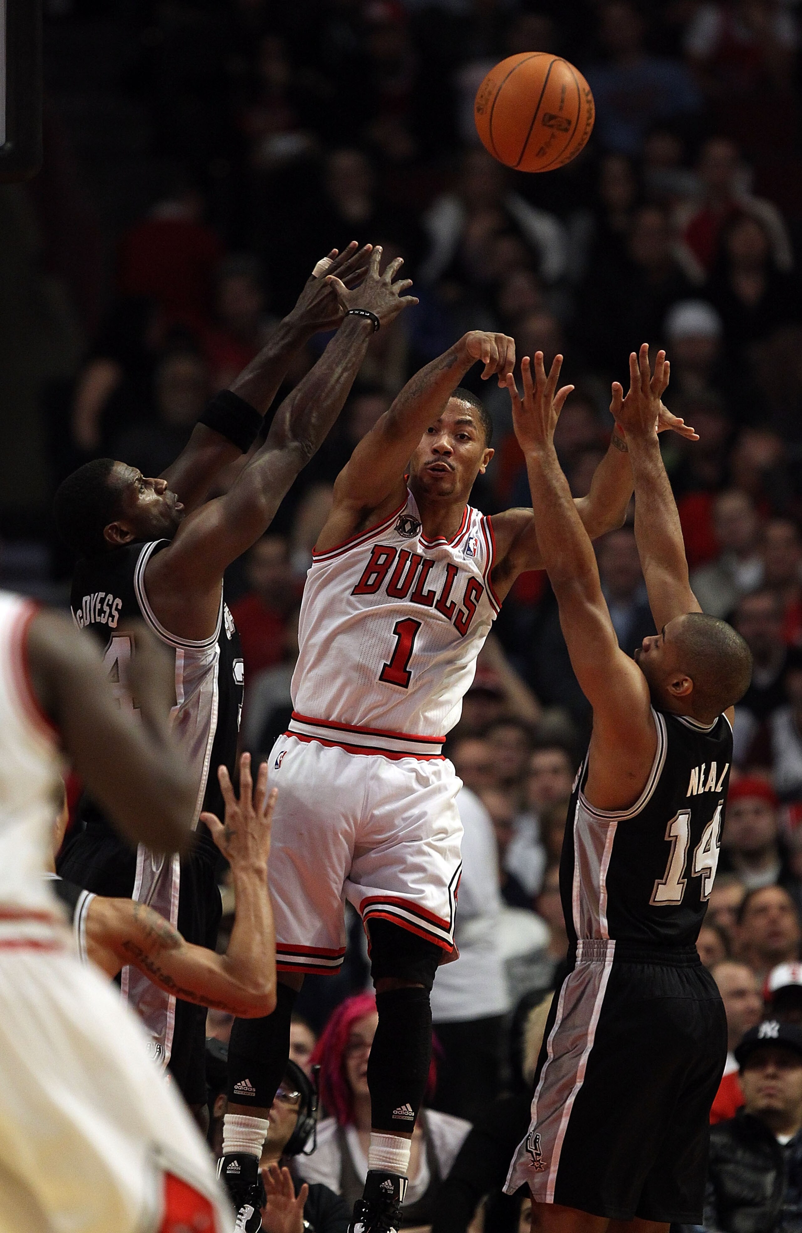 CHICAGO, IL - FEBRUARY 17: Derrick Rose #1 of the Chicago Bulls leaps to pass between Antonio McDyess #34 and Gary Neal #14 of the San Antonio Spurs at the United Center on February 17, 2011 in Chicago, Illinois. NOTE TO USER: User expressly acknowledges 