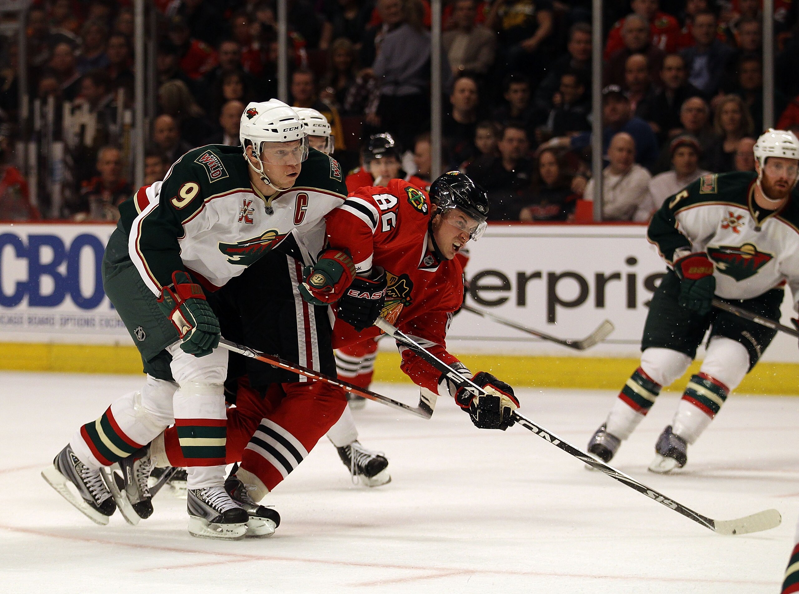 CHICAGO, IL - FEBRUARY 16: Tomas Kopecky #82 of the Chicago Blackhawks fires a shot under pressure from Mikko Koivu #9 of the Minnesota Wild at the United Center on February 16, 2011 in Chicago, Illinois. The Blackhawks defeated the Wild 3-1.  (Photo by J