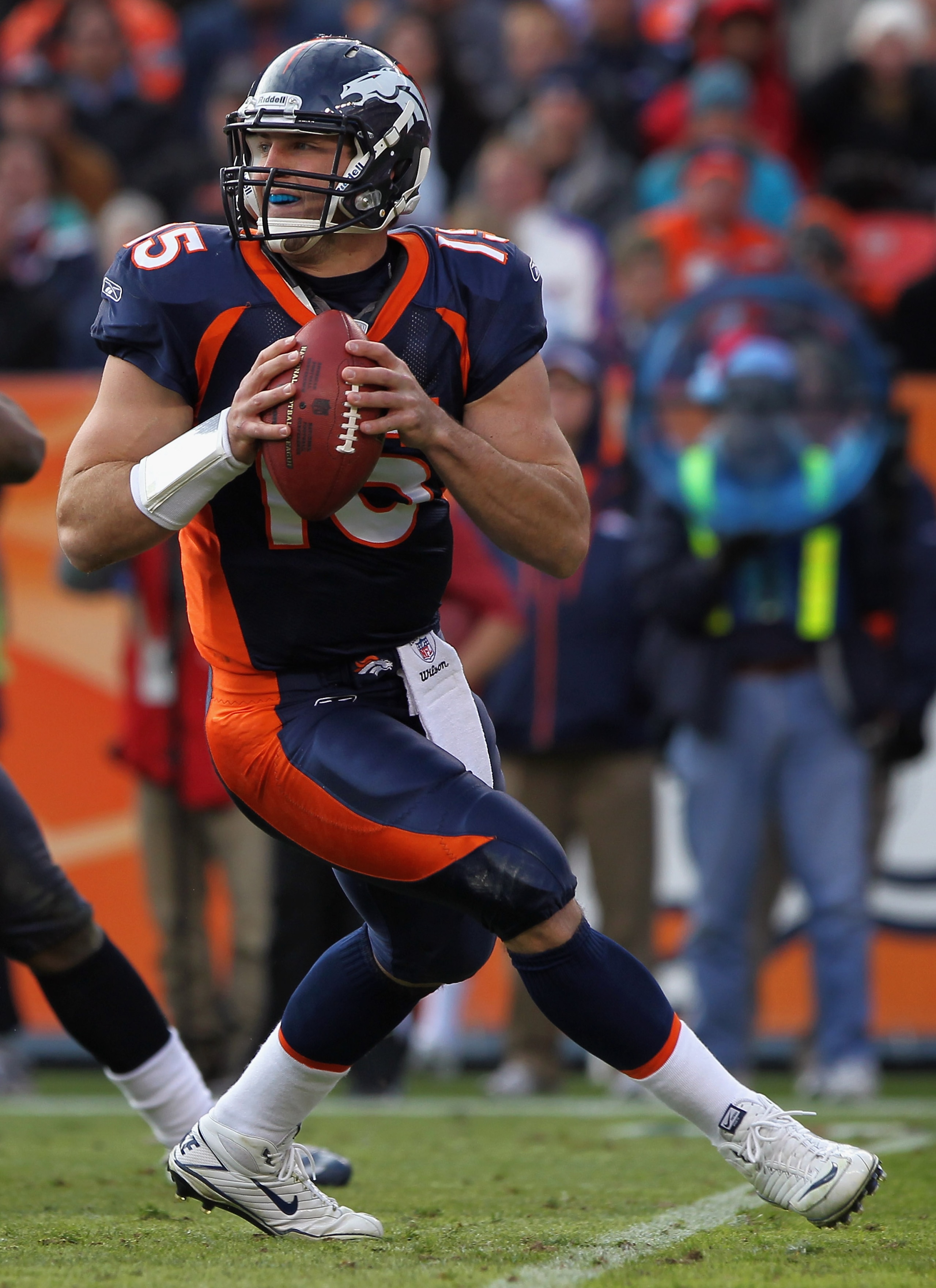 DENVER - DECEMBER 26:  Quarterback Tim Tebow #15 of the Denver Broncos rolls out and looks to deliver a pass against the Houston Texas at INVESCO Field at Mile High on December 26, 2010 in Denver, Colorado. The Broncos defeated the Texans 24-23.  (Photo b