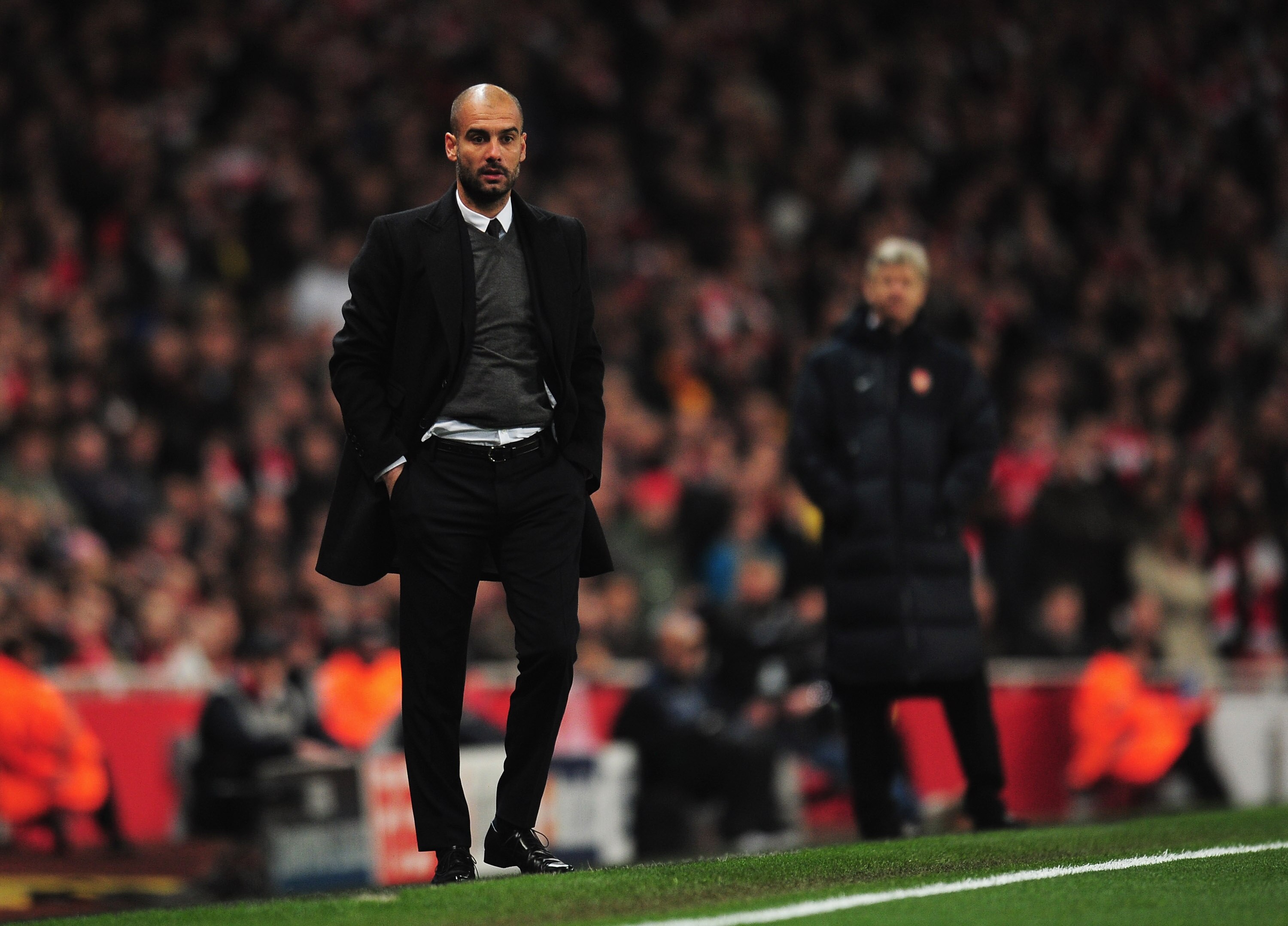 LONDON, ENGLAND - FEBRUARY 16:  Josep Guardiola, Coach of Barcelona watches with Arsene Wenger, Manager of Arsenal during the UEFA Champions League round of 16 first leg match between Arsenal and Barcelona at the Emirates Stadium on February 16, 2011 in L
