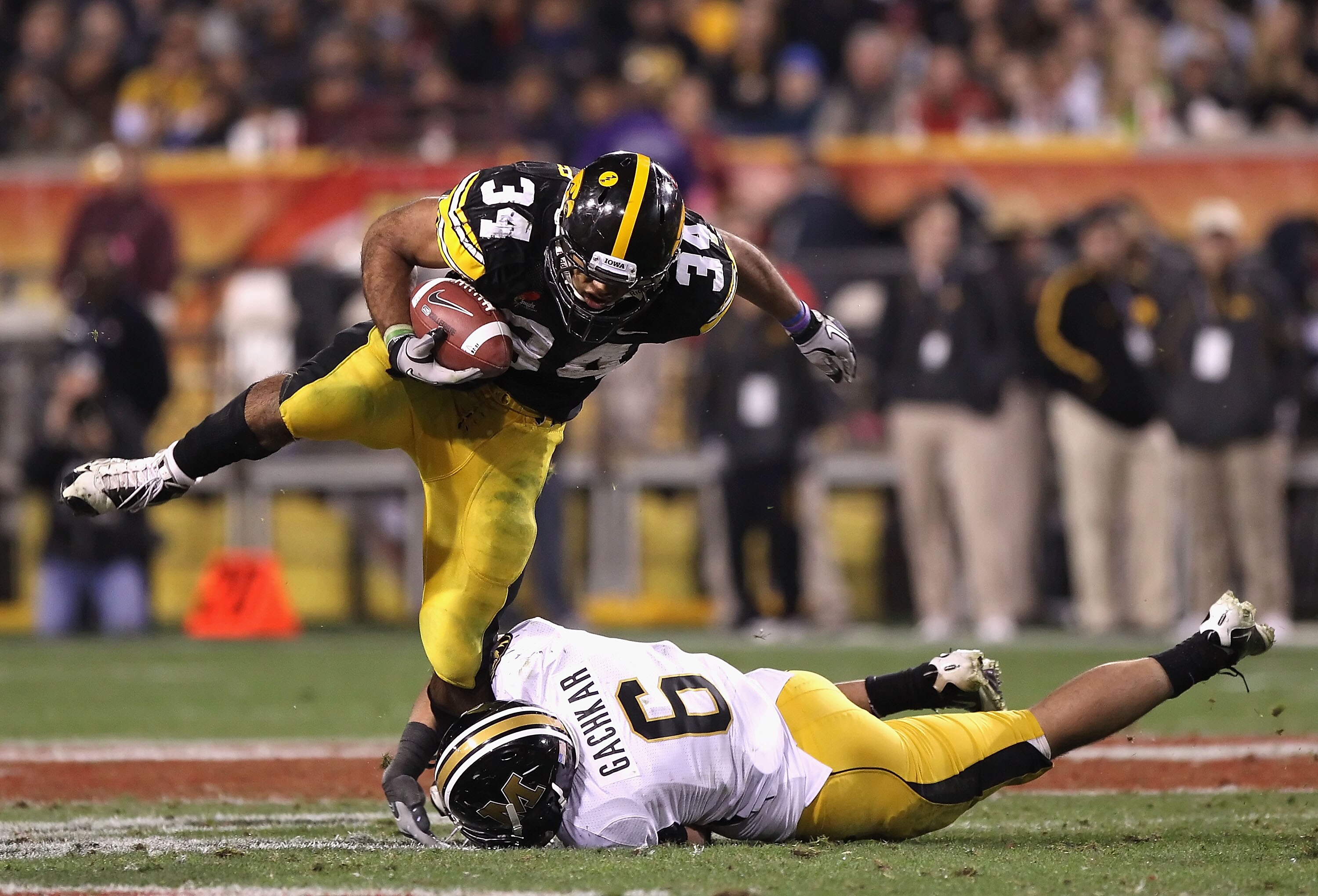 TEMPE, AZ - DECEMBER 28:  Runningback Marcus Coker #34 of the Iowa Hawkeyes rushes the football over Andrew Gachkar #6 of the Missouri Tigers during the Insight Bowl at Sun Devil Stadium on December 28, 2010 in Tempe, Arizona.  The Hawkeyes defeated the T