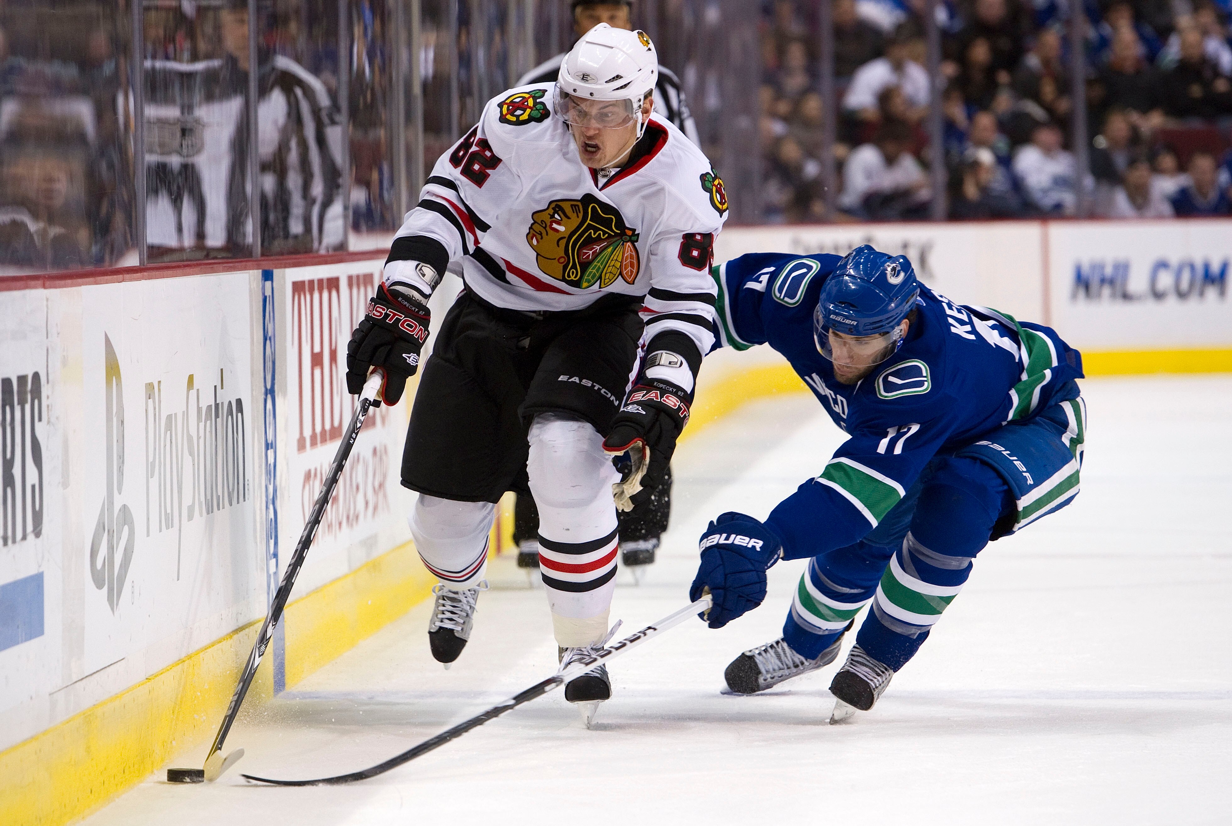 VANCOUVER, CANADA - FEBRUARY 4: Ryan Kesler #17 of the Vancouver Canucks tries to poke the puck away from Tomas Kopecky #82 of the Chicago Blackhawks during the first period in NHL action on February 04, 2011 at Rogers Arena in Vancouver, British Columbia