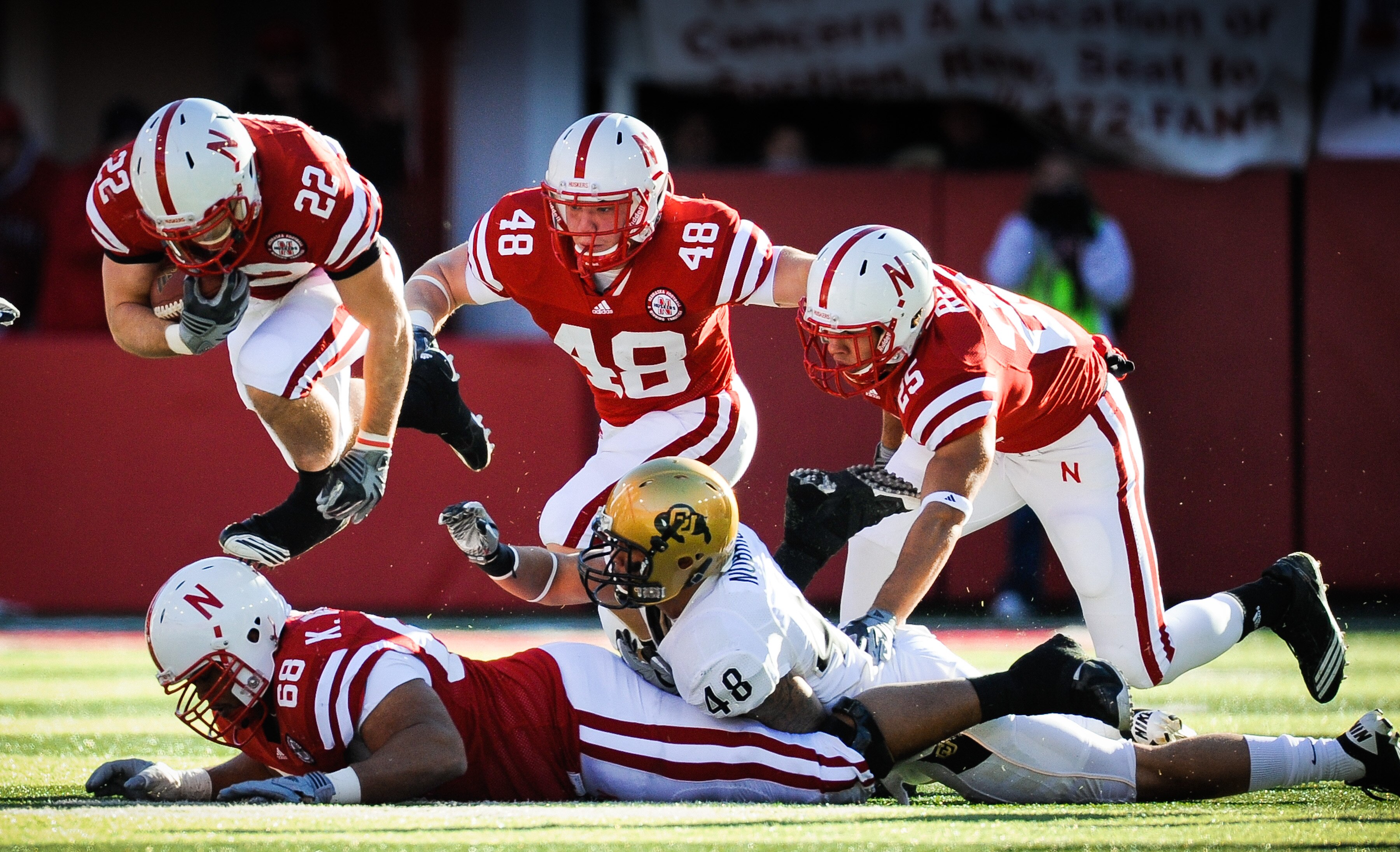 LINCOLN, NE - NOVEMBER 26: Rex Burkhead #22 of the Nebraska Cornhuskers leaps over teammate Keith Williams #68 and is helped by Tyler Legate #48 and Kyler Reed #25 of the Nebraska Cornhuskers during their game against the Colorado Buffaloes at Memorial St