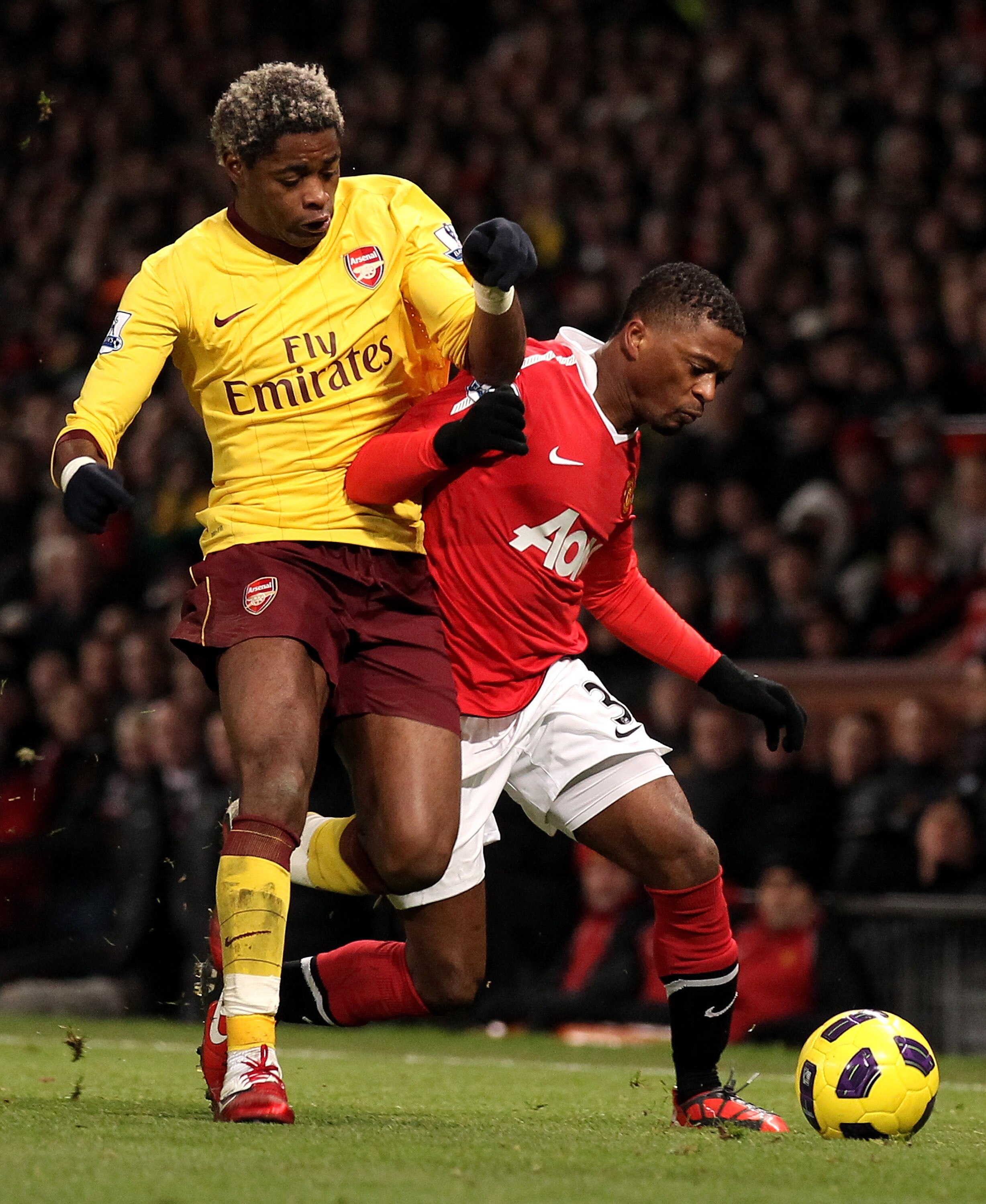 MANCHESTER, ENGLAND - DECEMBER 13:  Patrice Evra of Manchester United battles for the ball with Alexandre Song of Arsenal during the Barclays Premier League match between Manchester United and Arsenal at Old Trafford on December 13, 2010 in Manchester, En