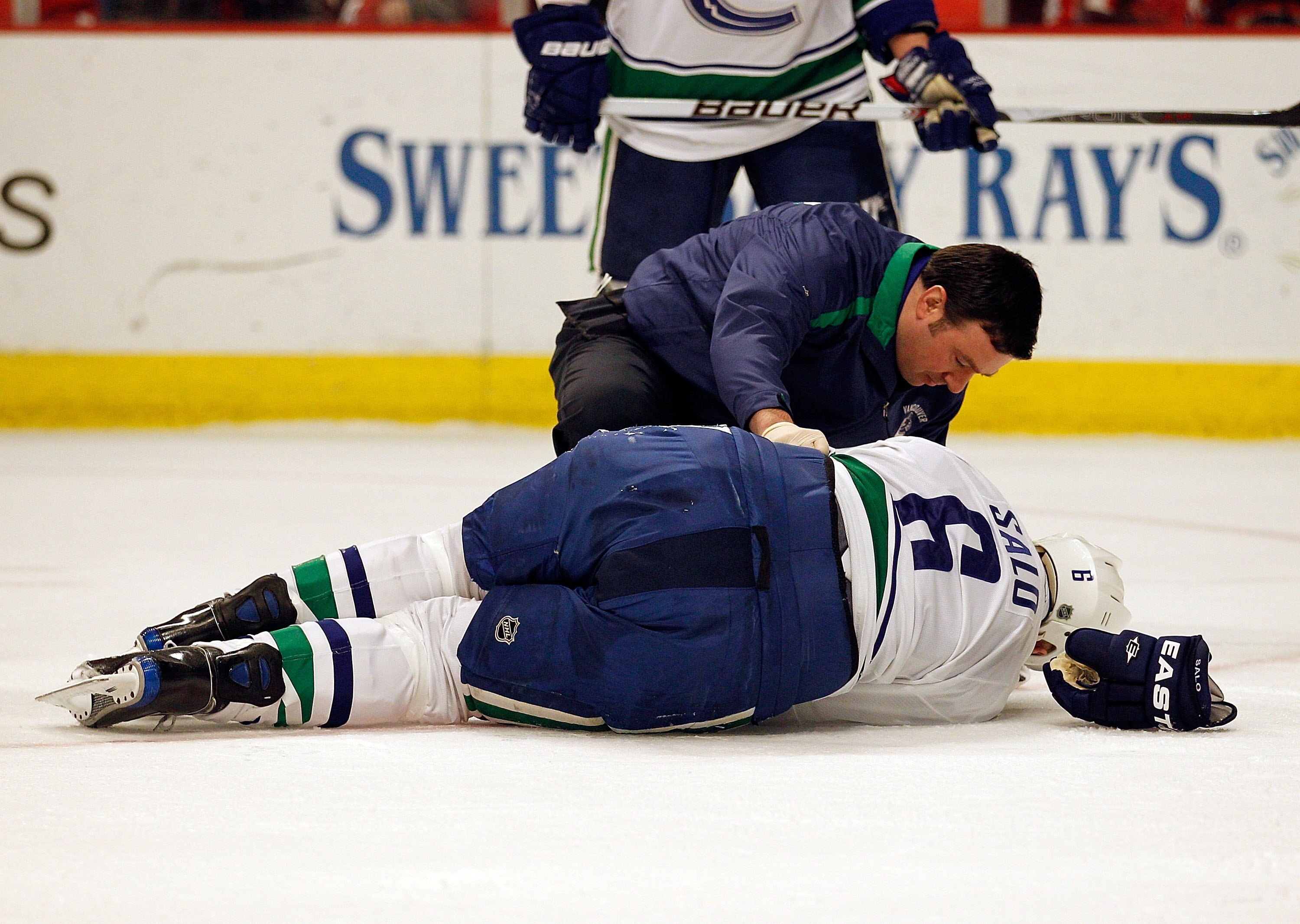 CHICAGO - MAY 09: A trainer attends to Sami Salo #6 of the Vancouver Canucks at the end of the first period after Salo suffered an injury against the Chicago Blackhawks in Game Five of the Western Conference Semifinals during the 2010 NHL Stanley Cup Play
