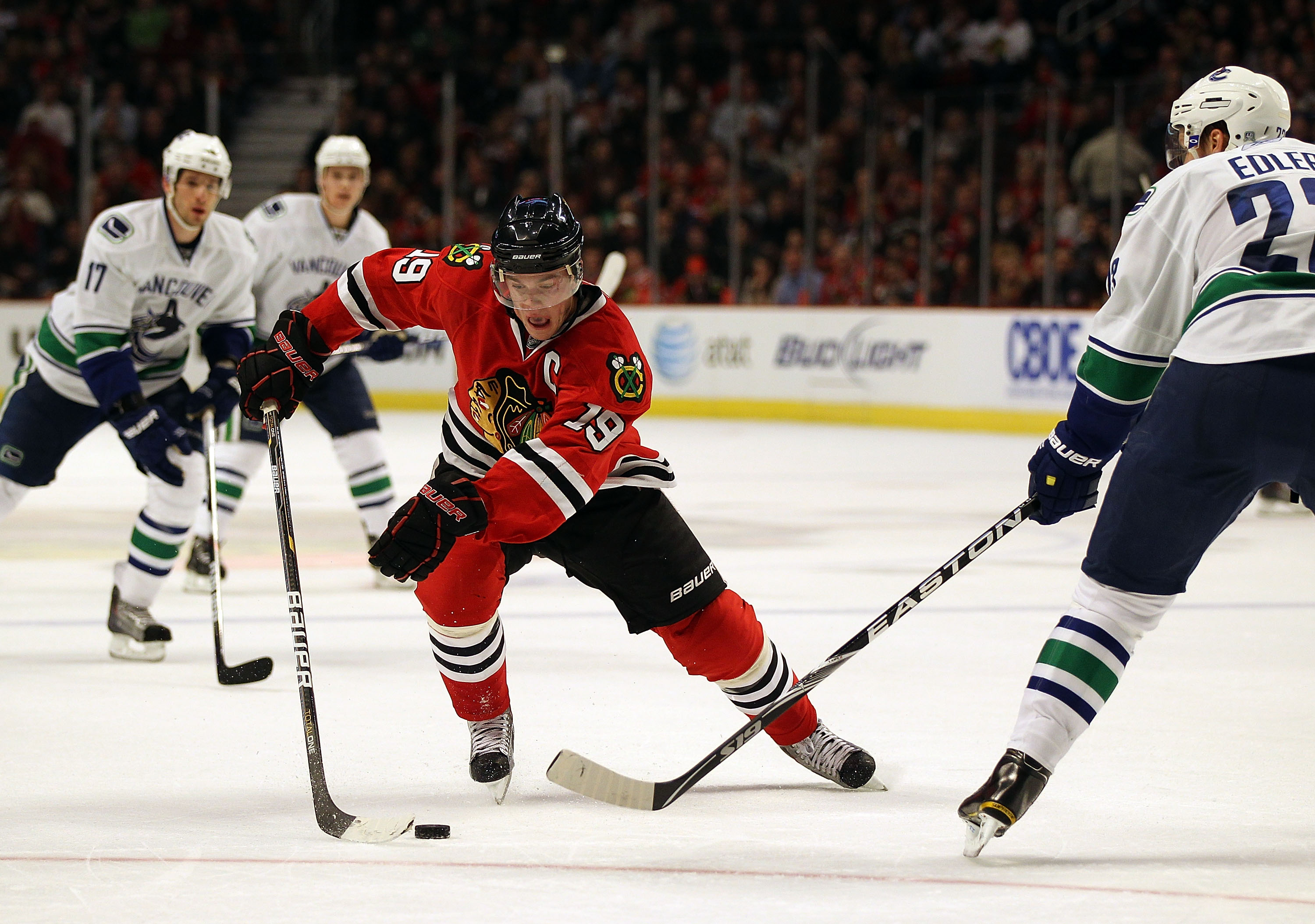 CHICAGO, IL - DECEMBER 03: Jonathan Toews #19 of the Chicago Blackhawks controls the puck against Alexander Edler #23 of the Vancouver Canucks at the United Center on December 3, 2010 in Chicago, Illinois. The Canucks defeated the Blackhawks 3-0.  (Photo