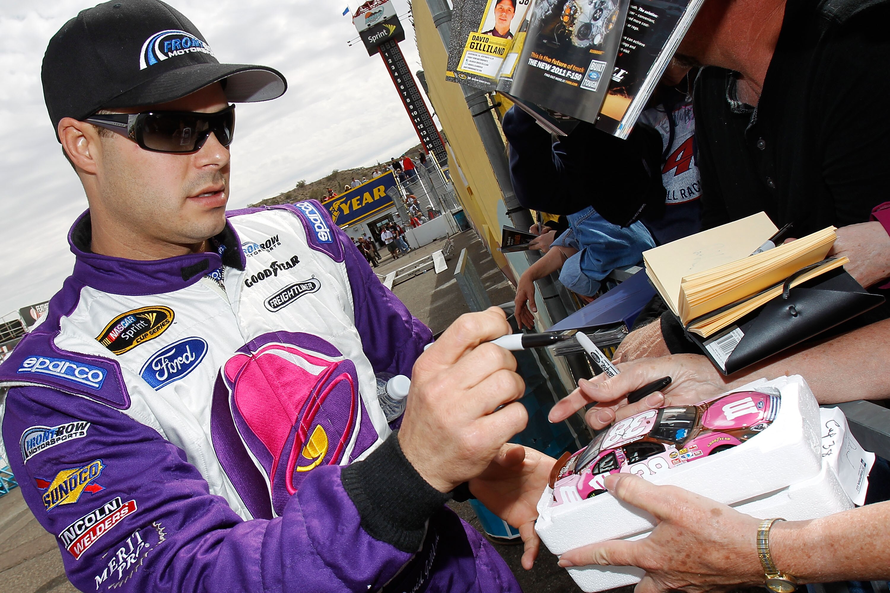 AVONDALE, AZ - FEBRUARY 26:  David Gilliland, driver of the #34 Taco Bell Ford, signs autographs for fans during qualifying for the NASCAR Sprint Cup Series Subway Fresh Fit 500 at Phoenix International Raceway on February 26, 2011 in Avondale, Arizona.
