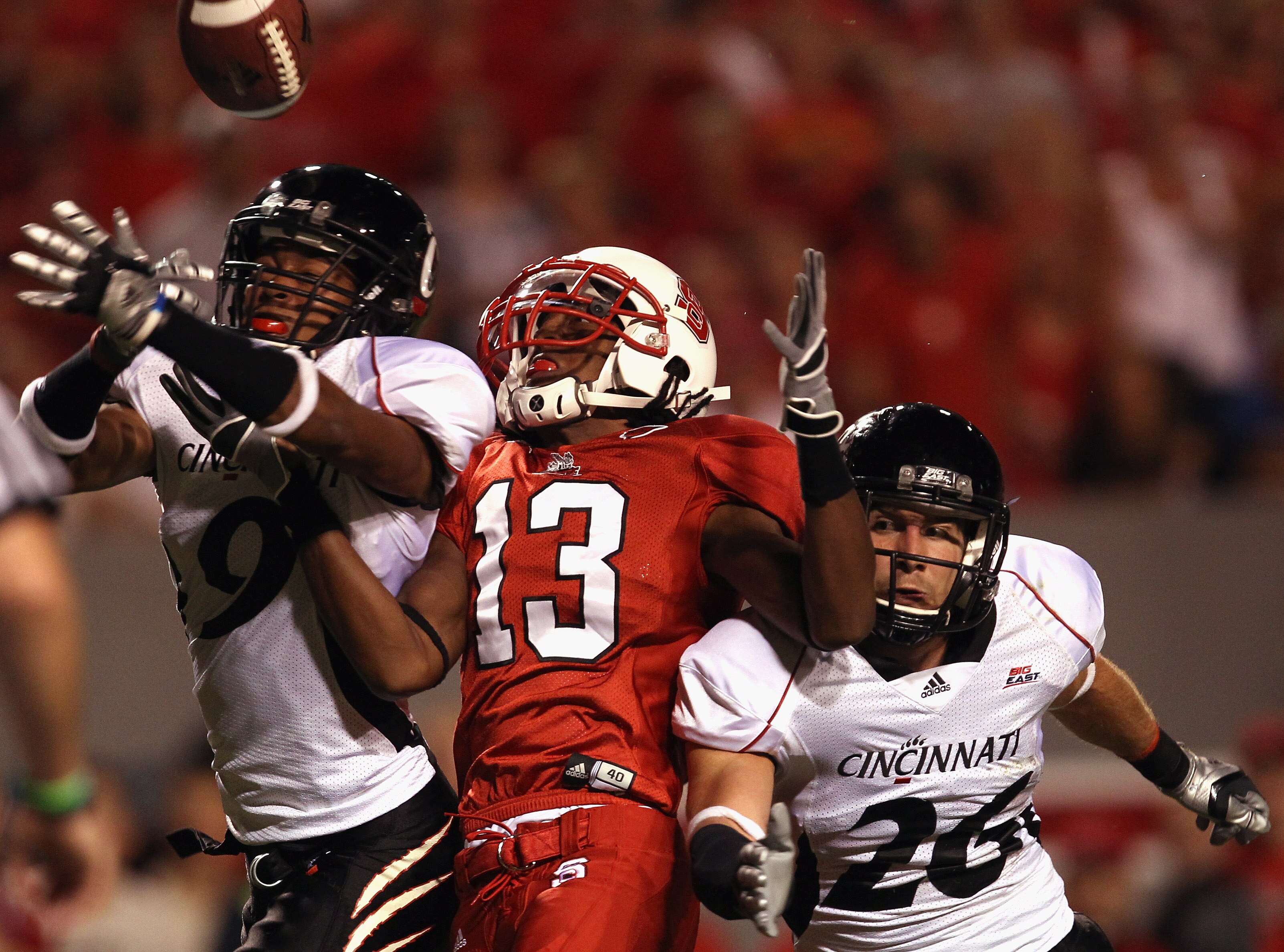 RALEIGH, NC - SEPTEMBER 16:  Teammates Dominique Battle #9 and Drew Frey #26 of the Cincinnati Bearcats break up a pass to Owen Spencer #13 of the North Carolina State Wolfpack during their game at Carter-Finley Stadium on September 16, 2010 in Raleigh, N