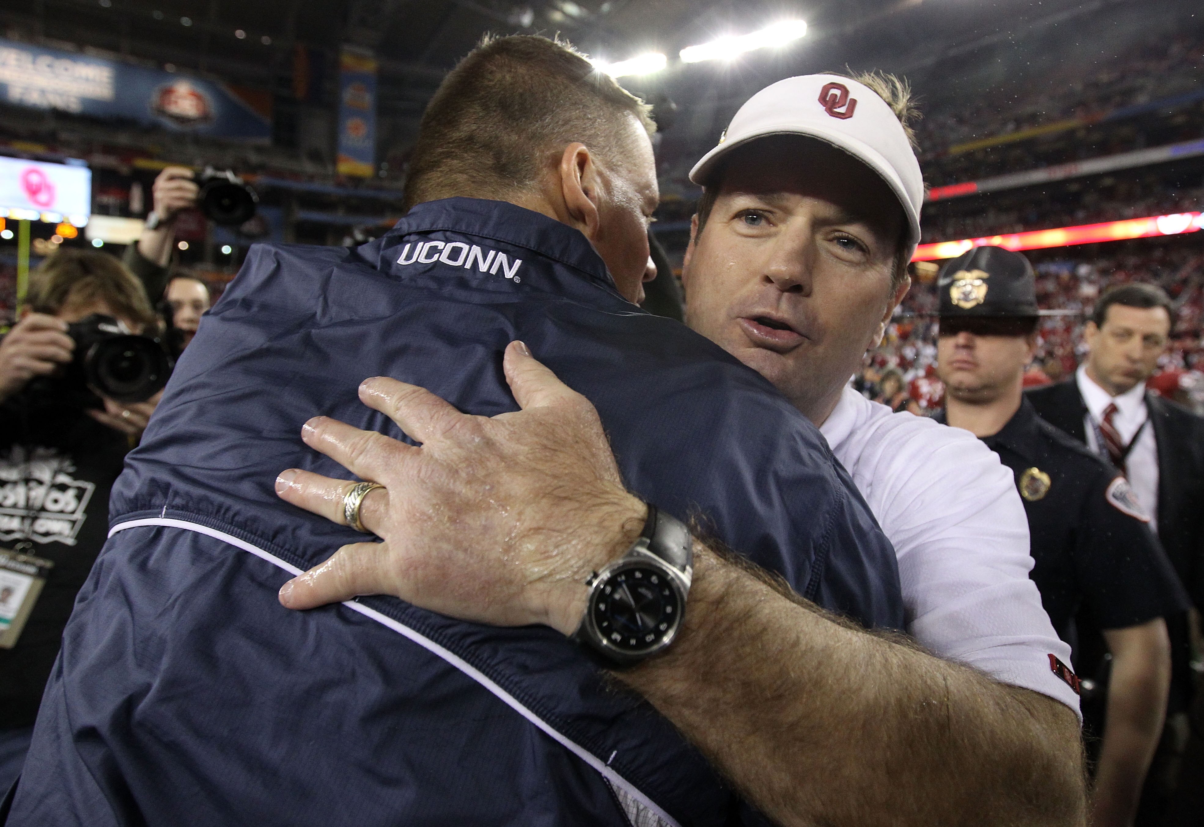 GLENDALE, AZ - JANUARY 01:  Head coach Bob Stoops of the Oklahoma Sooners hugs head coach Randy Edsall of the Connecticut Huskies after the Sooners 48-20 victory in the Tostitos Fiesta Bowl at the Universtity of Phoenix Stadium on January 1, 2011 in Glend