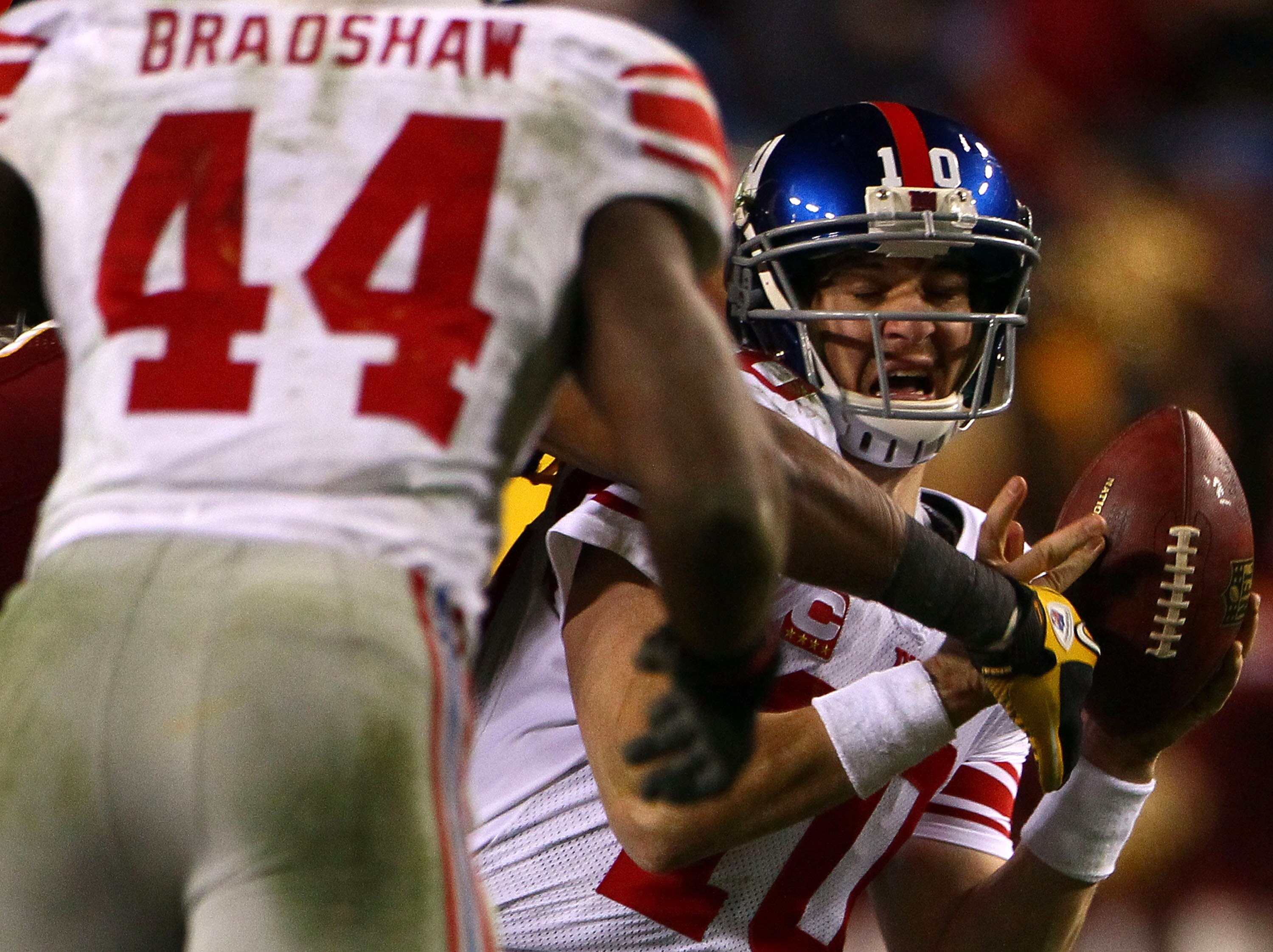 LANDOVER, MD - JANUARY 02:  Quarterback Eli Manning #10 of the New York Giants looks to Ahmad Bradshaw #44 to lateral the ball while being pressured by the Washington Redskins defense during their game at FedEx Field on January 2, 2011 in Landover, Maryla