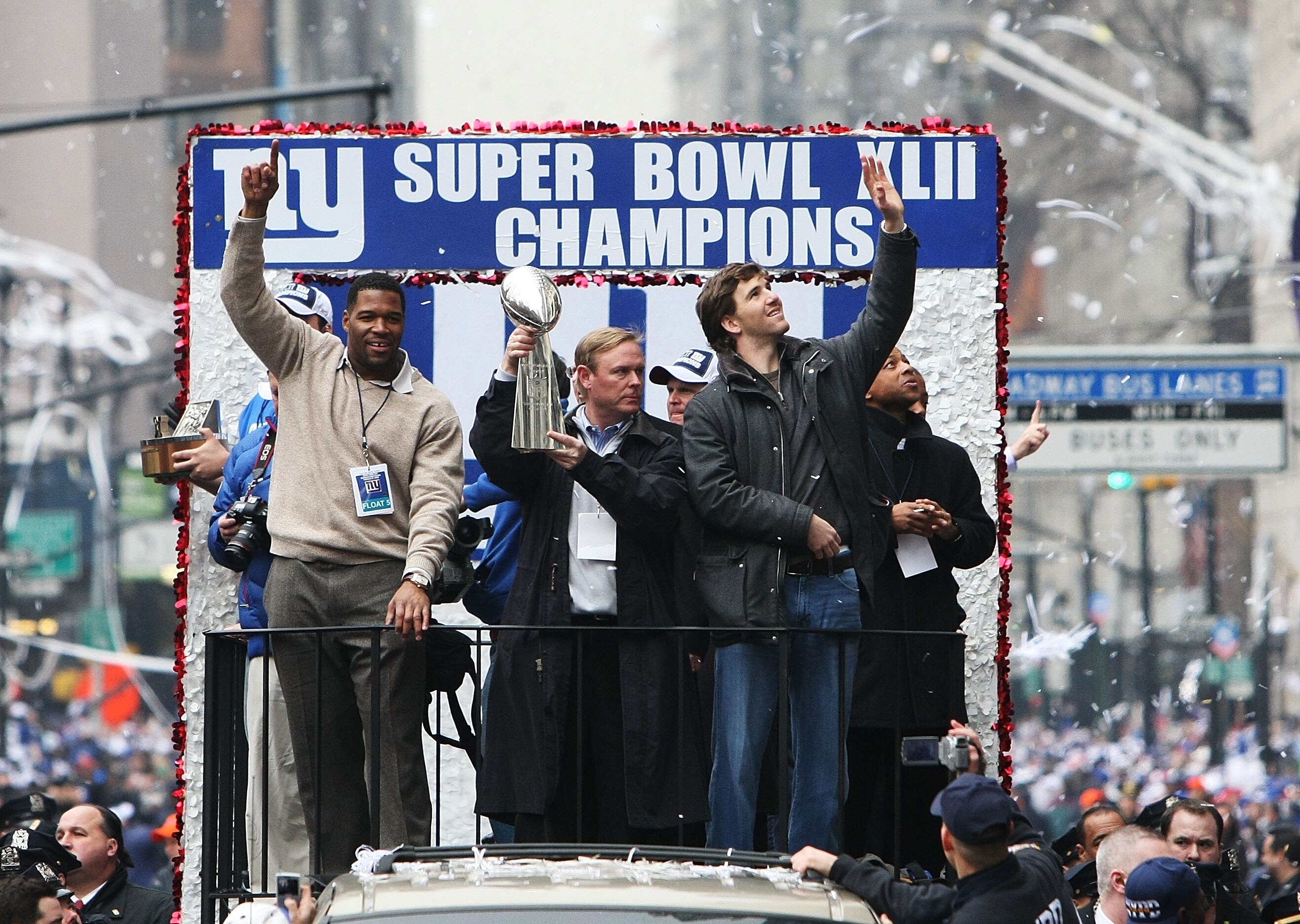 NEW YORK - FEBRUARY 05:  (L-R) Michael Strahan, Owner John Mara and Eli Manning of the New York Giants ride in a float along Broadway, also known as 'The Canyon of Heroes' during Super Bowl XLII victory parade in New York City.  (Photo by Al Bello/Getty I