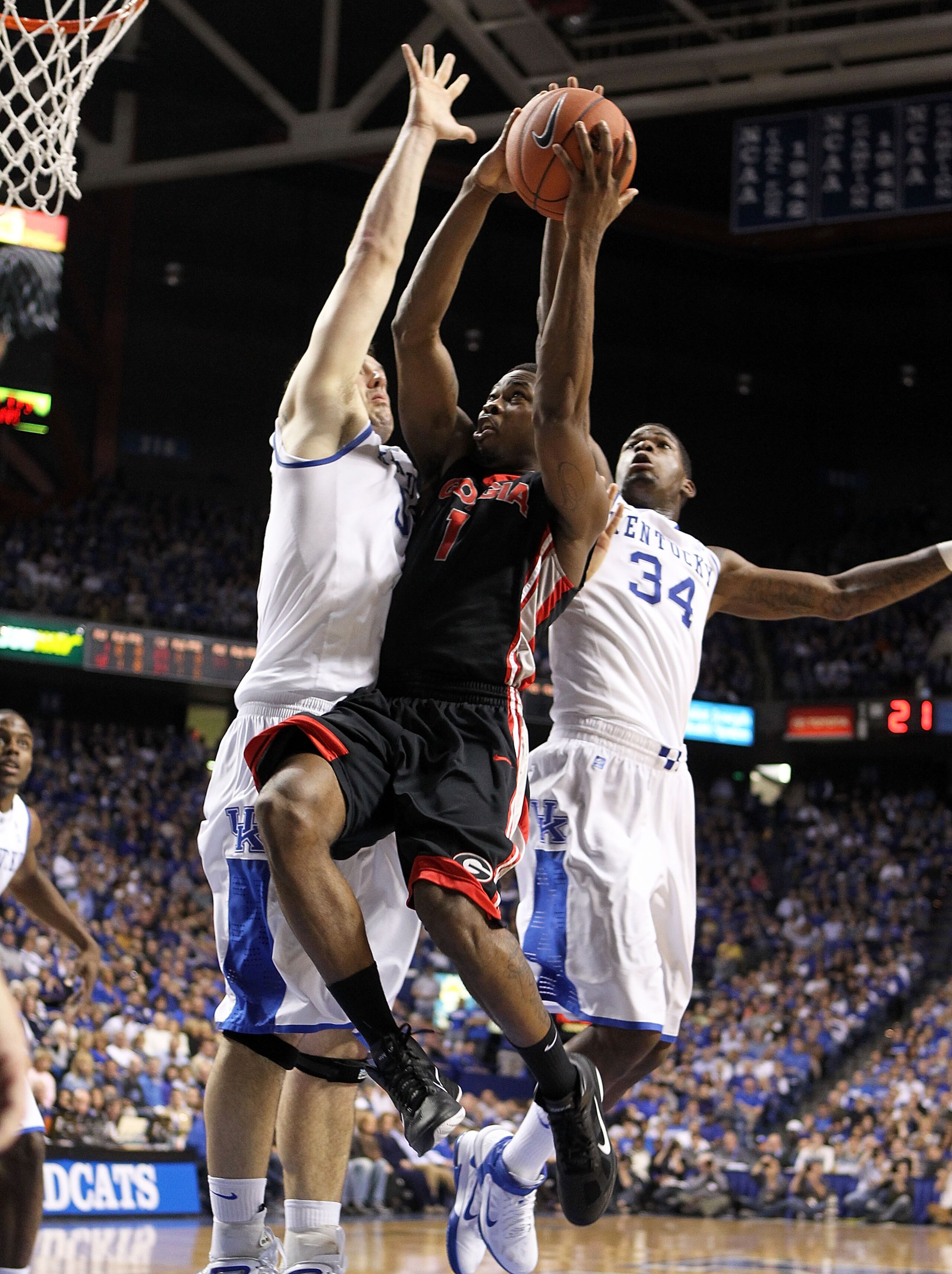 LEXINGTON, KY - JANUARY 29:  Travis Leslie #1 of  the Georgia Bulldogs shoots the ball while defended by Josh Harrellson #55 and DeAndre Liggins #34 of the Kentucky Wildcats during the SEC game against at Rupp Arena on January 29, 2011 in Lexington, Kentu