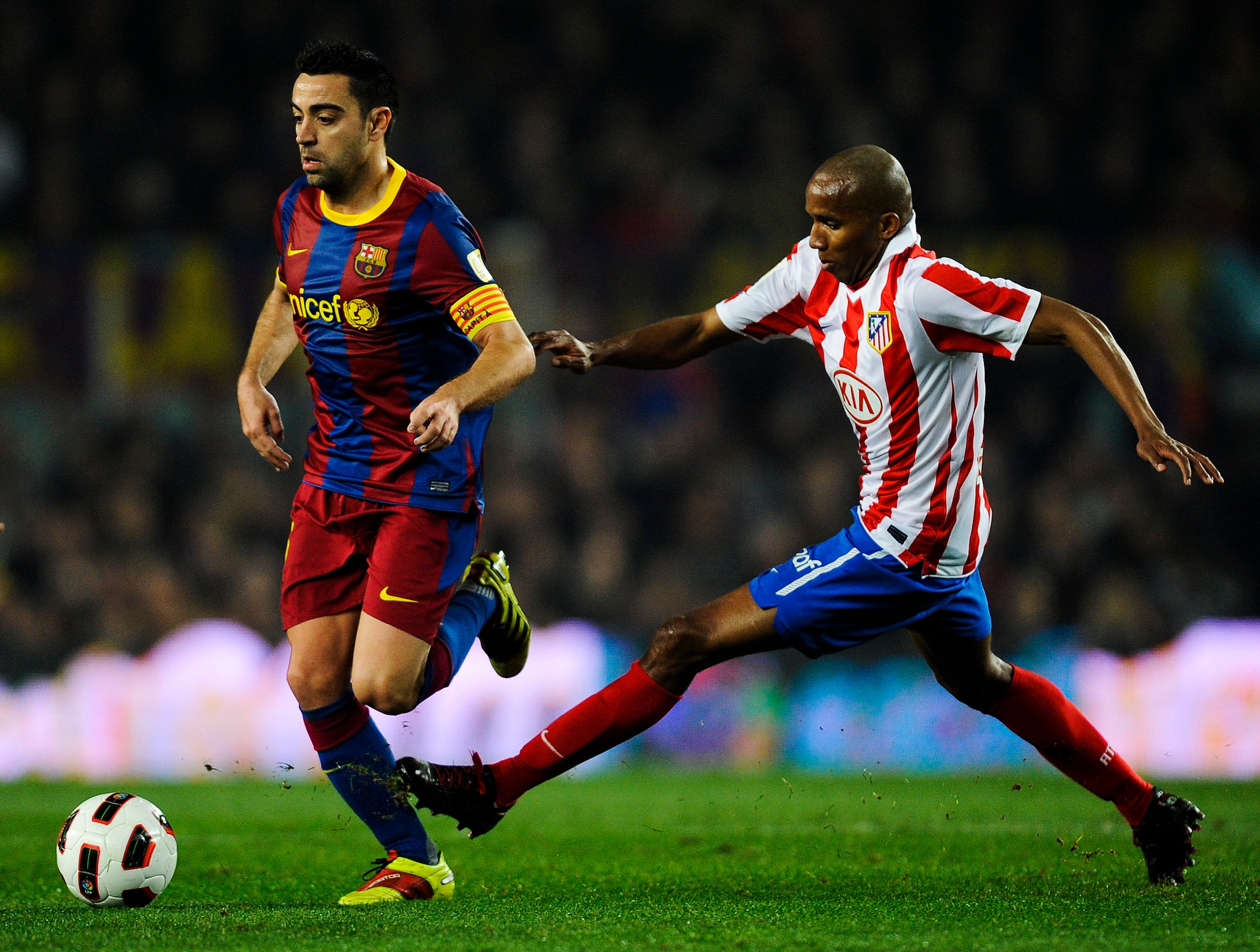 BARCELONA, SPAIN - FEBRUARY 05:  Xavi Hernandez of Barcelona (L) is chased by Paulo AssunÂao of Atletico Madrid during the La Liga match between Barcelona and Atletico de Madrid at Camp Nou on February 5, 2011 in Barcelona, Spain.  (Photo by David Ramos/G