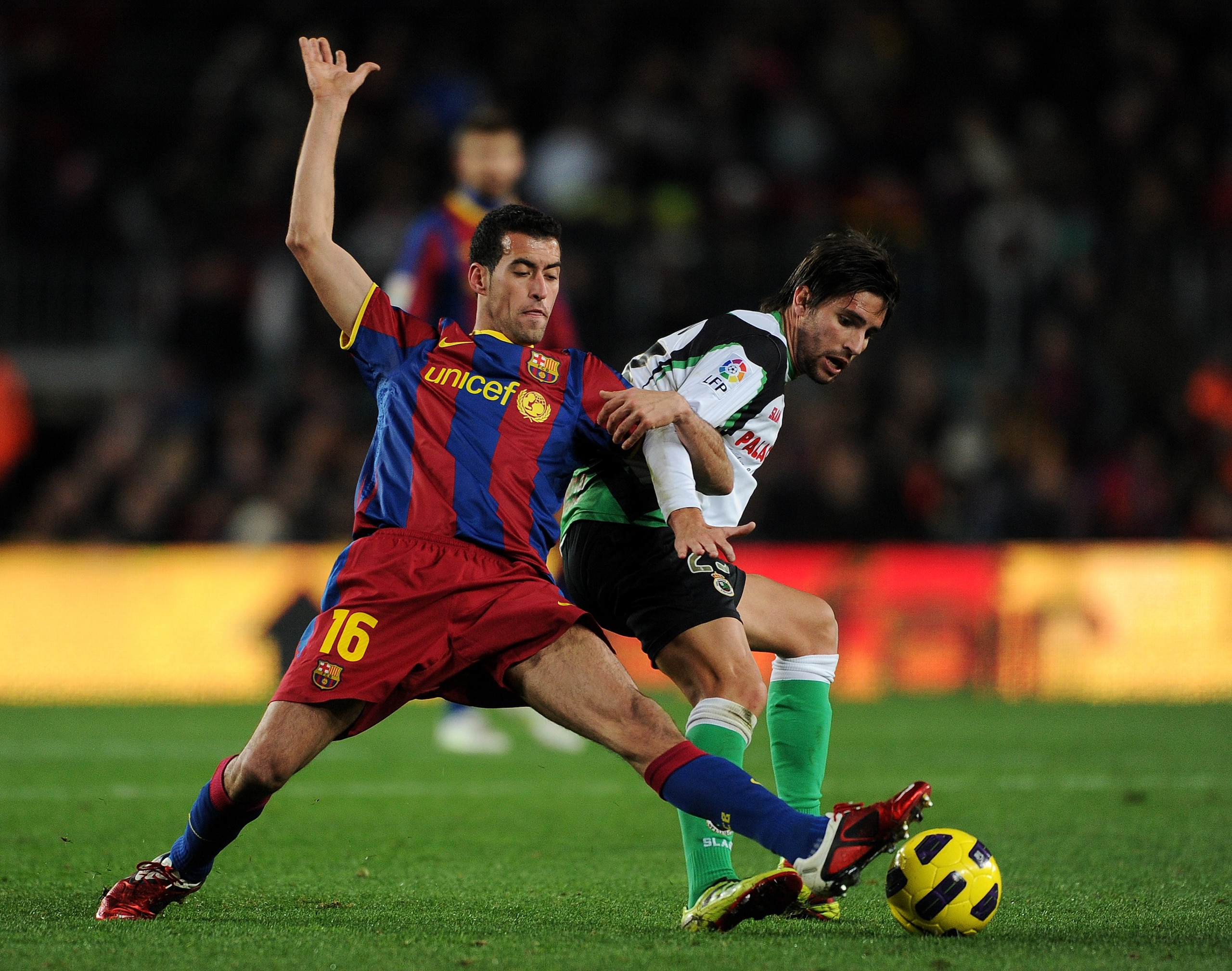 BARCELONA, SPAIN - JANUARY 22:  Sergio Busquets (L) of Barcelona duels for the ball with Christian Fernandez of Racing Santander during the la liga match between Barcelona and Racing Santander at the Camp Nou stadium on January 22, 2011 in Barcelona, Spai