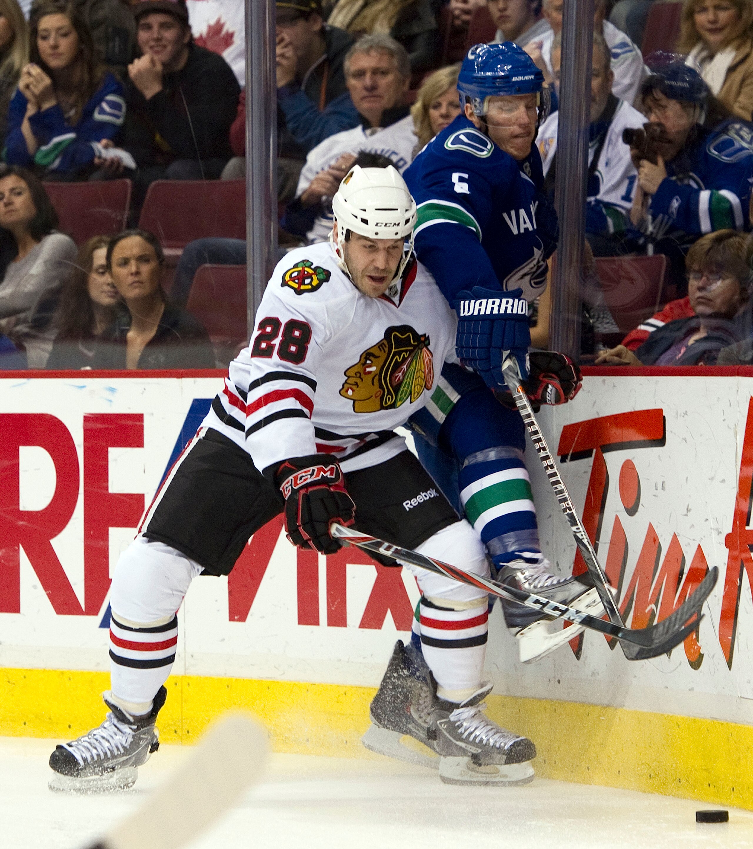 VANCOUVER, CANADA - FEBRUARY 4: Jake Dowell #28 of the Chicago Blackhawks pins Christian Ehrhoff #5 of the Vancouver Canucks up against the end boards during the first period in NHL action on February 04, 2011 at Rogers Arena in Vancouver, British Columbi