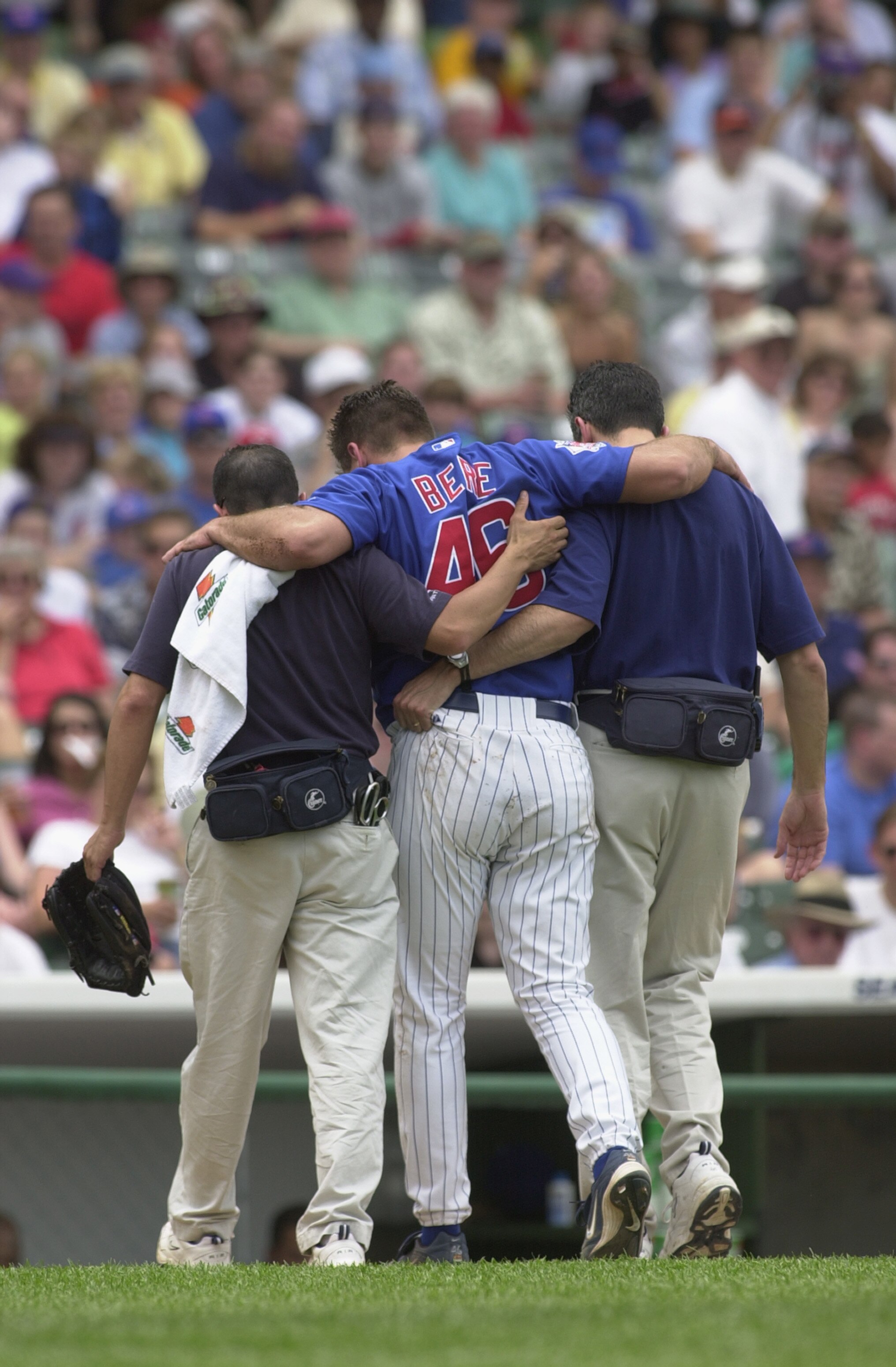 CHICAGO - JUNE 26:  Pitcher Jason Bere #46 of the Chicago Cubs is helped off the field by the training staff after getting injured against the Cincinnati Reds during the game on June 26, 2002 at Wrigley Field in Chicago, Illinois. The Reds defeated the Cu