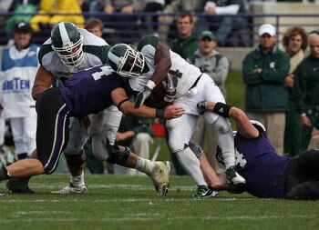 EVANSTON, IL - OCTOBER 23: Edwin Baker #4 of the Michigan State Spartans is tackled by Nate Williams #44 and Vince Browne #94 of the Northwestern Wildcats at Ryan Field on October 23, 2010 in Evanston, Illinois. Michigan State defeated Northwestern 35-27.