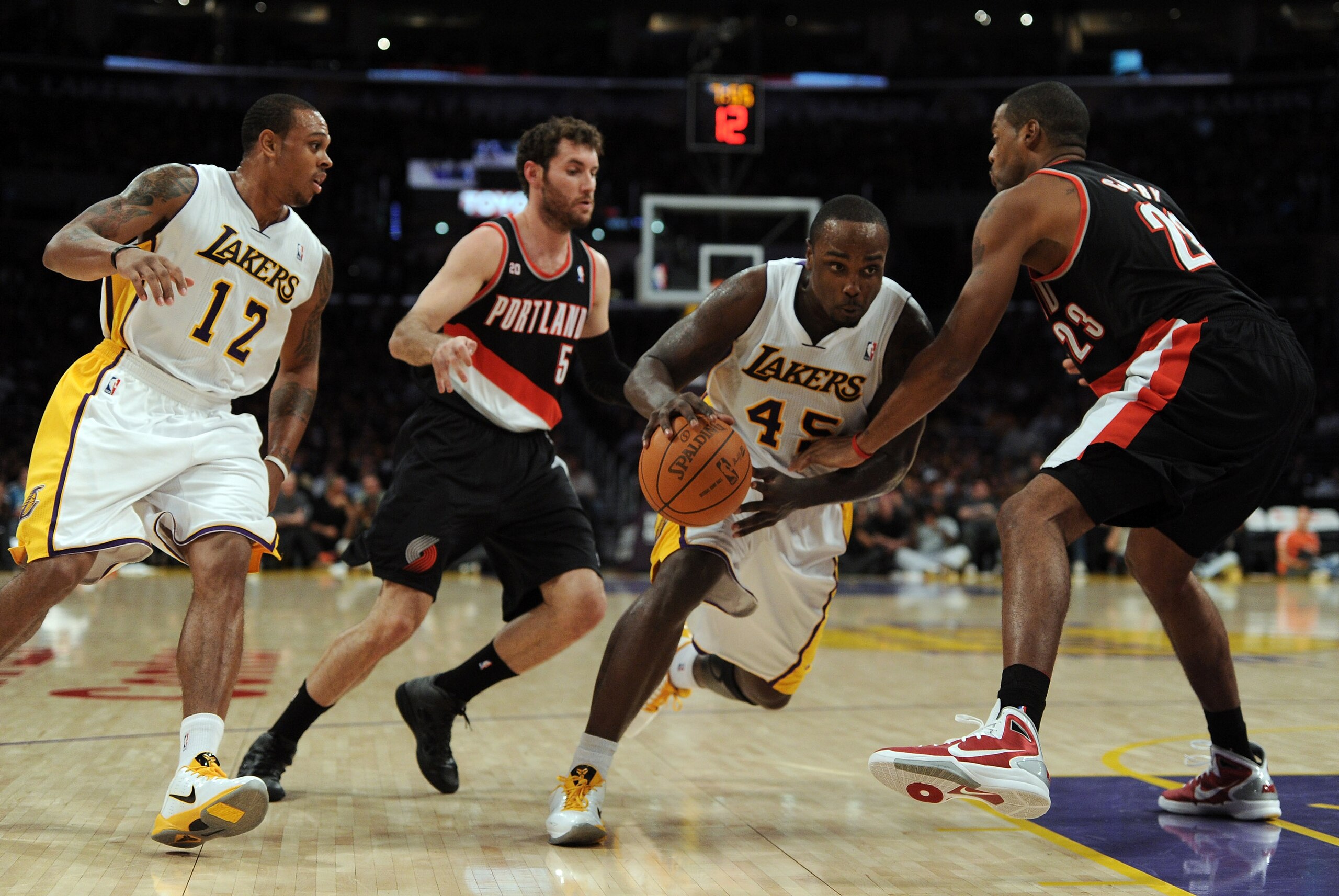 LOS ANGELES, CA - NOVEMBER 07:  Derrick Caracter #45 of the Los Angeles Lakers dribbles between Marcus Camby #23 and Rudy Fernandez #5 of the Portland Trail Blazers as Shannon Brown #12 looks on at the Staples Center on November 7, 2010 in Los Angeles, Ca