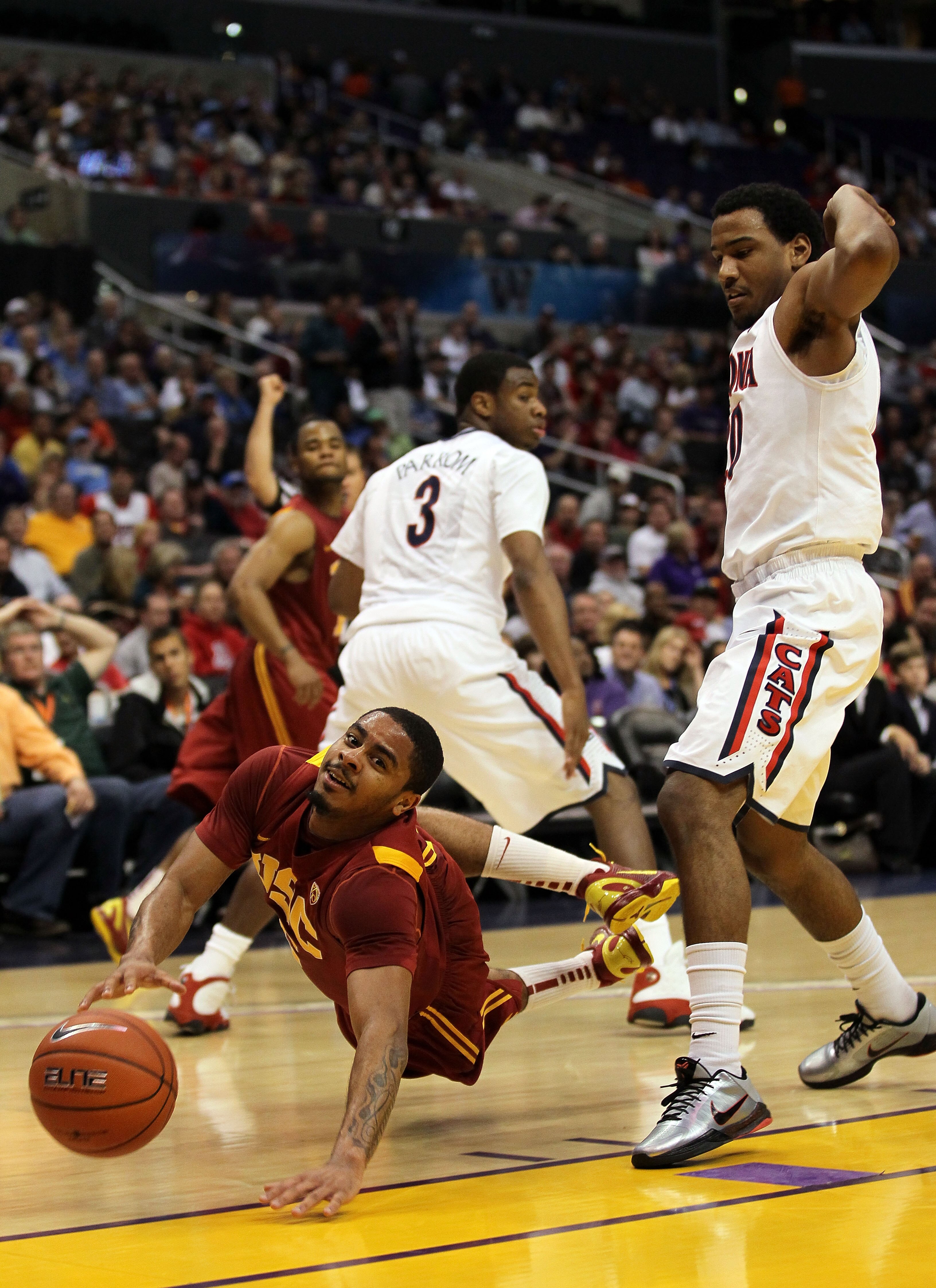LOS ANGELES, CA - MARCH 11:  Jio Fontan #2 of the USC Trojans falls to the ground as he is fouled by Jordin Mayes #20 of the Arizona Wildcats in the first half in the semifinals of the 2011 Pacific Life Pac-10 Men's Basketball Tournament at Staples Center