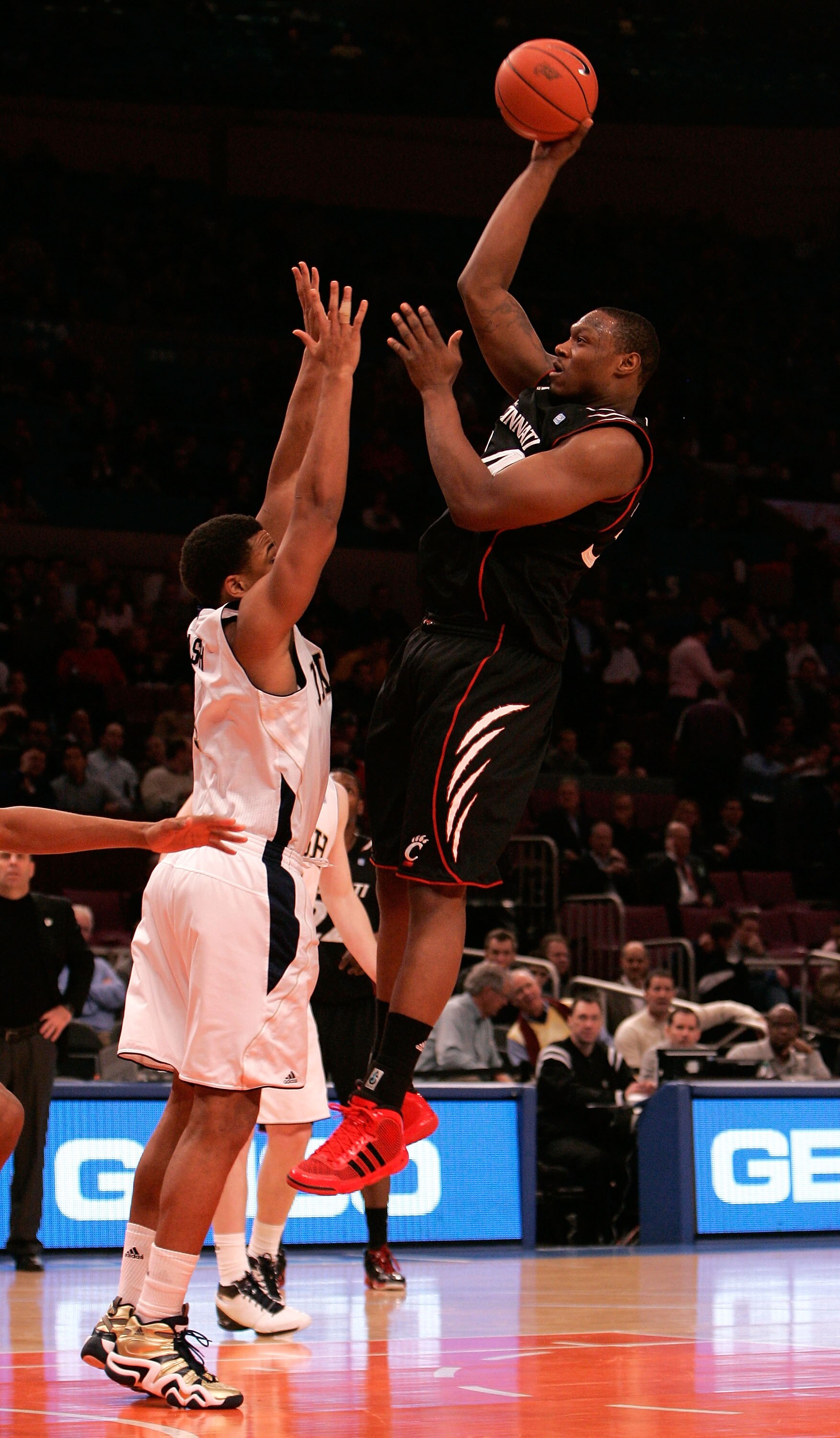 NEW YORK, NY - MARCH 10: Yancy Gates #34 of the Cincinnati Bearcats shoots over Tyrone Nash #1 of the Notre Dame Fighting Irish during the quarterfinals of the 2011 Big East Men's Basketball Tournament presented by American Eagle Outfitters  at Madison Sq