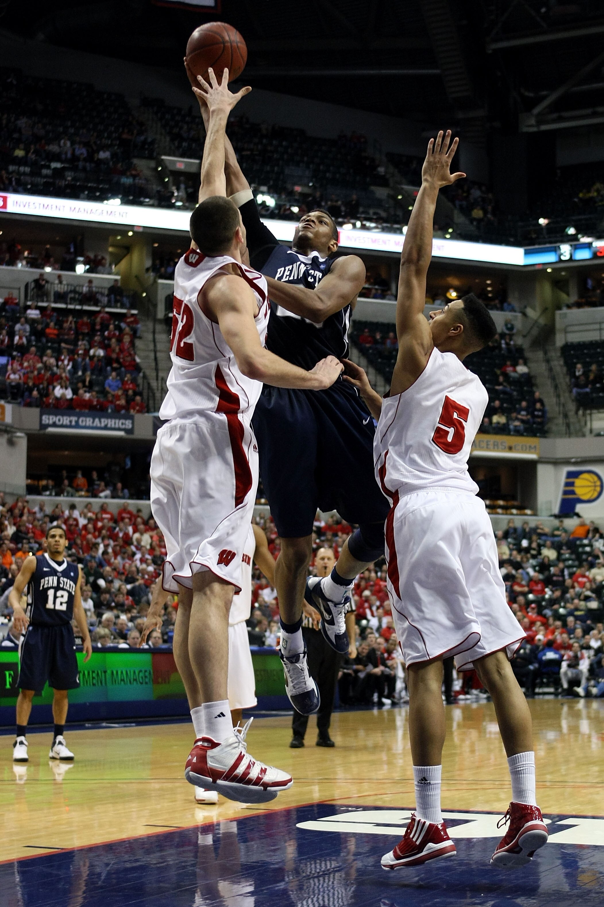 INDIANAPOLIS, IN - MARCH 11:  Jeff Brooks #25 of the Penn State Nittany Lions attempts a shot against Keaton Nankivil #52 and Ryan Evans #5 of the Wisconsin Badgers during the quarterfinals of the 2011 Big Ten Men's Basketball Tournament at Conseco Fieldh