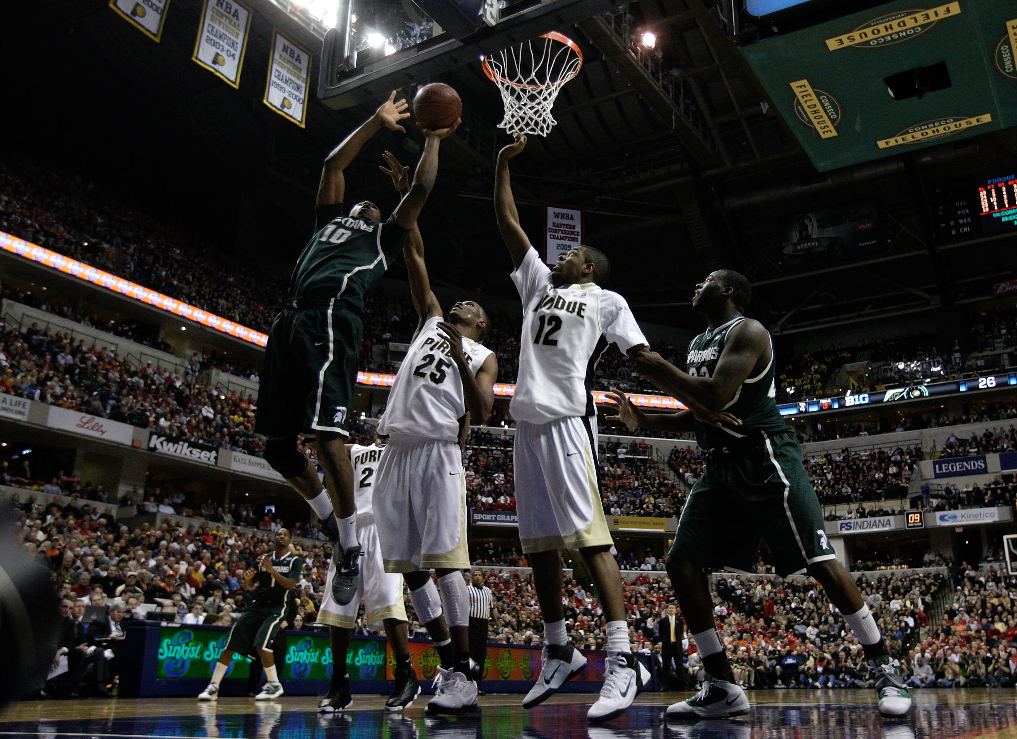 INDIANAPOLIS, IN - MARCH 11:  Delvon Roe #10 of the Michigan State Spartans attempts a shot against JaJuan Johnson #25 and Kelsey Barlow #12 of the Purdue Boilermakers during the quarterfinals of the 2011 Big Ten Men's Basketball Tournament at Conseco Fie