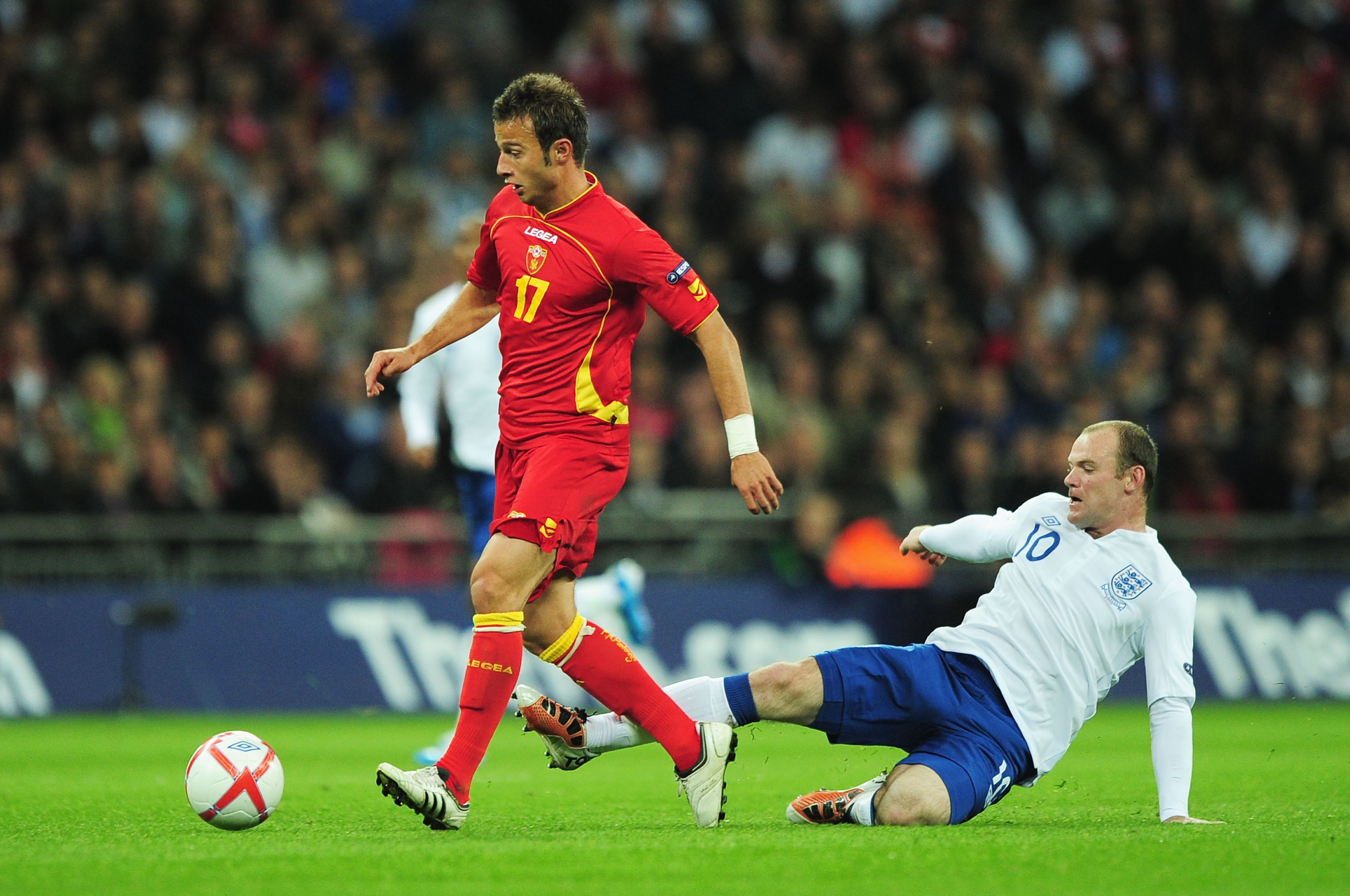 LONDON, ENGLAND - OCTOBER 12:  Wayne Rooney of England tackles Elsad Zverotic of Montenegro after which he was  shown a yellow card for the challenge during the UEFA EURO 2012 Group G Qualifying match between England and Montenegro at Wembley Stadium on O