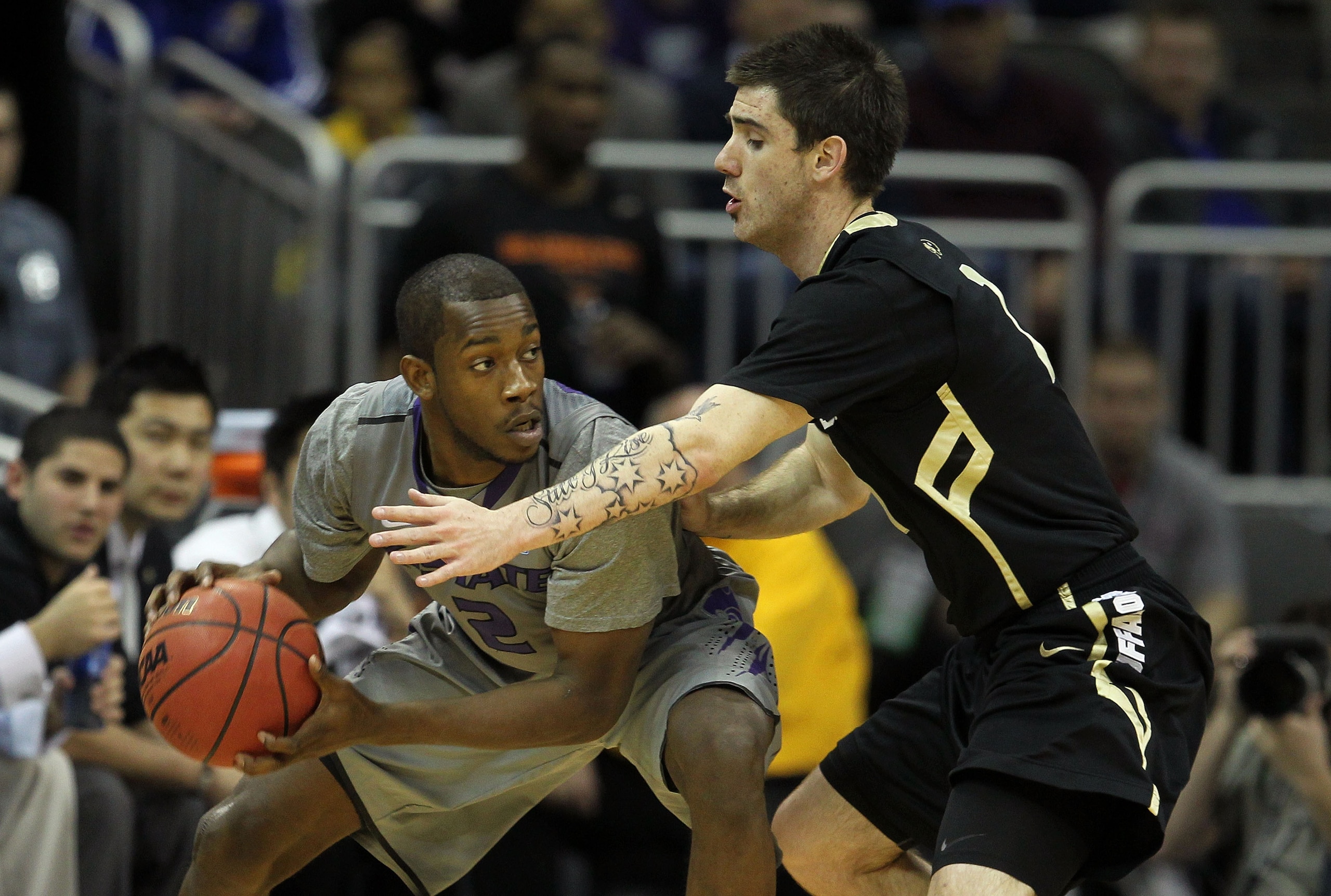 KANSAS CITY, MO - MARCH 10:  Devon Peterson #2 of the Kansas State Wildcats looks to move the ball as Nate Tomlinson #1 of the Colorado Buffaloes defends during their quarterfinal game in the 2011 Phillips 66 Big 12 Men's Basketball Tournament at Sprint C