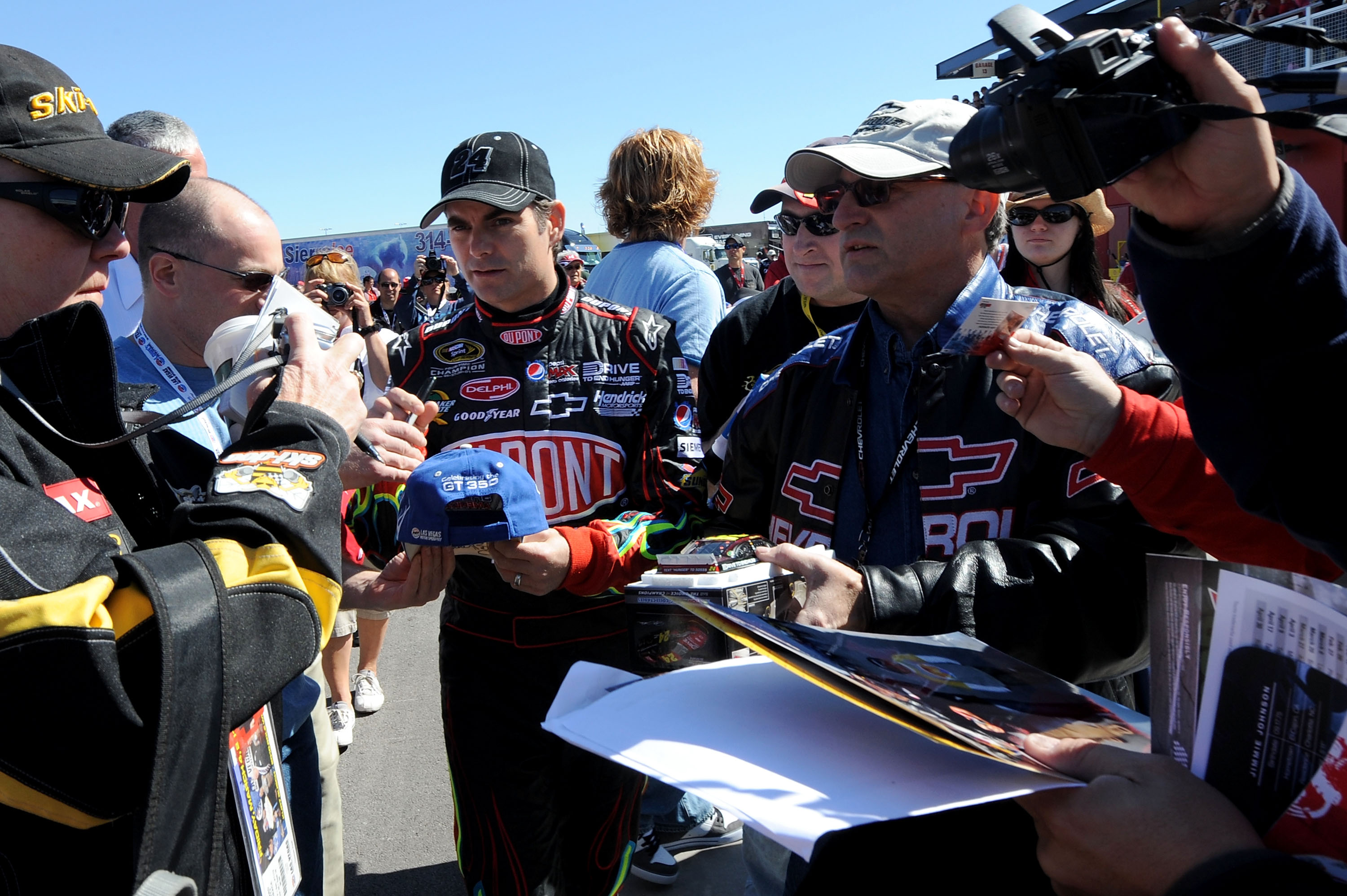 LAS VEGAS, NV - MARCH 04:  Jeff Gordon (C), driver of the #24 DuPont Chevrolet, signs autographs in the garage area during practice for the NASCAR Sprint Cup Series Kobalt Tools 400 at Las Vegas Motor Speedway on March 4, 2011 in Las Vegas, Nevada.  (Phot