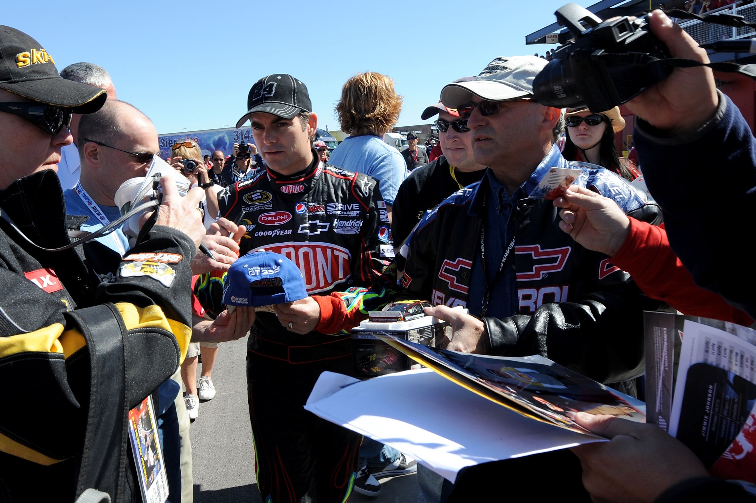 LAS VEGAS, NV - MARCH 04:  Jeff Gordon (C), driver of the #24 DuPont Chevrolet, signs autographs in the garage area during practice for the NASCAR Sprint Cup Series Kobalt Tools 400 at Las Vegas Motor Speedway on March 4, 2011 in Las Vegas, Nevada.  (Phot