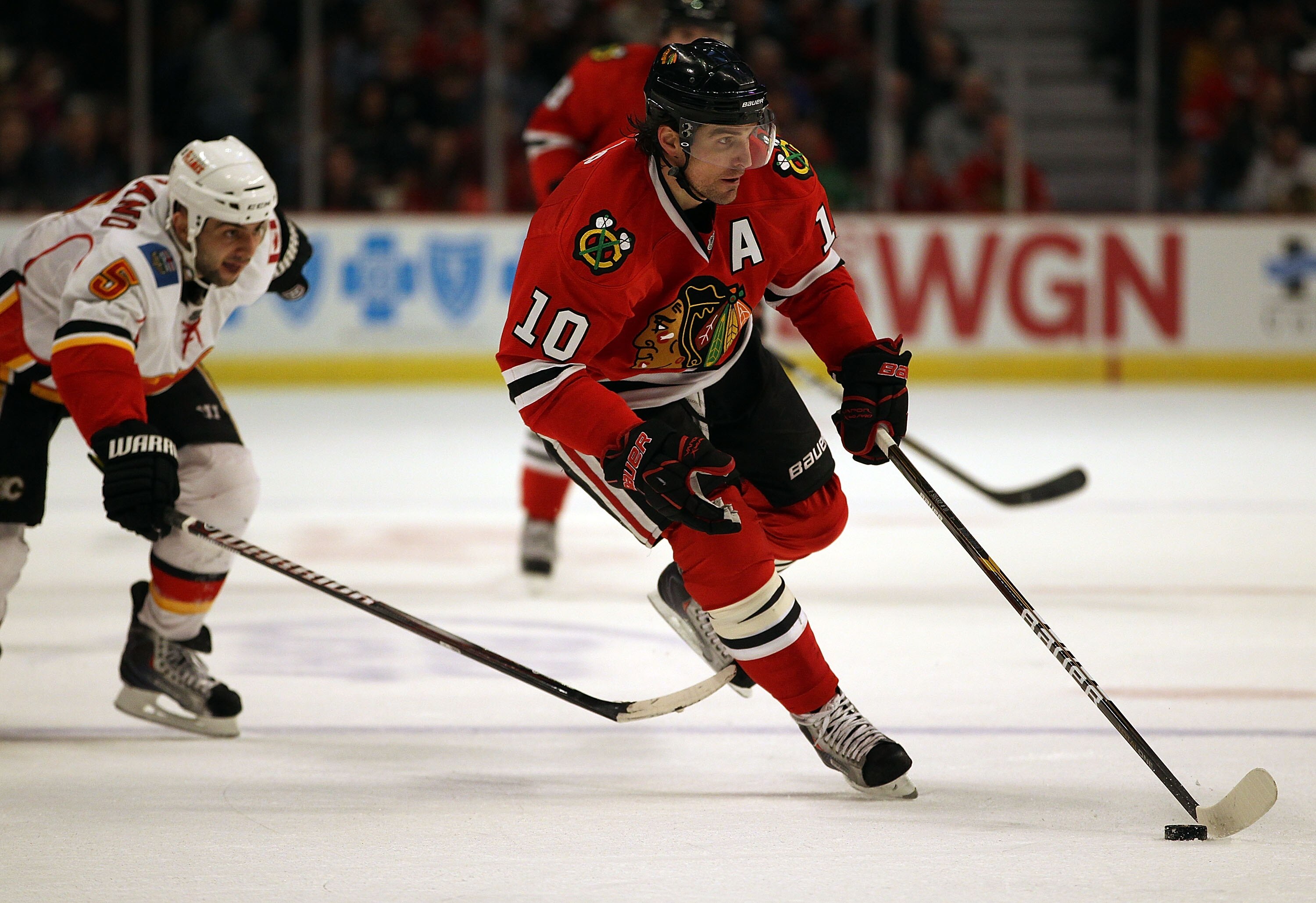 CHICAGO, IL - MARCH 02: Patrick Sharp #10 of the Chicago Blackhawks skates past Mark Giordano #5 of the Calgary Flames at the United Center on March 2, 2011 in Chicago, Illinois. (Photo by Jonathan Daniel/Getty Images)