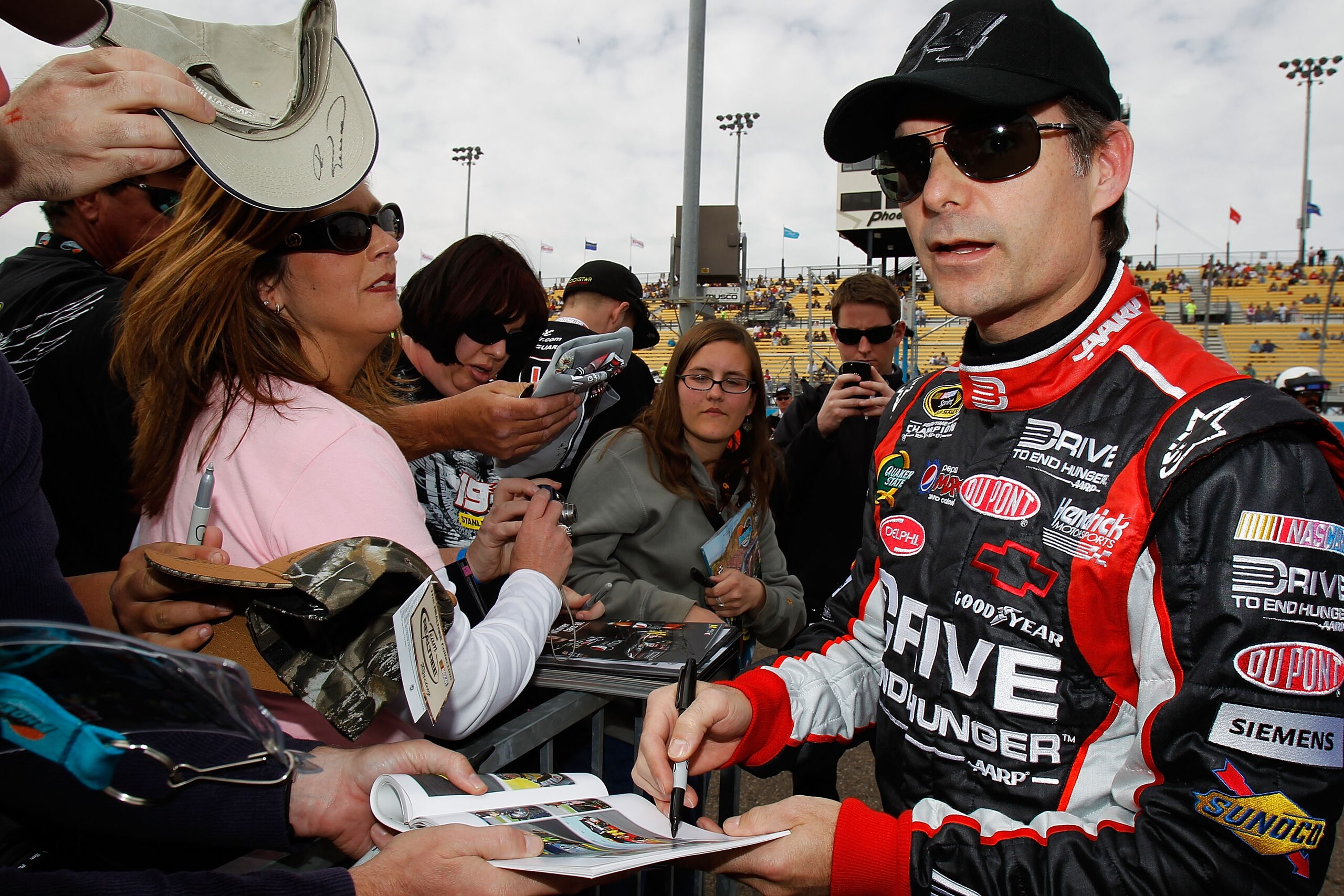 AVONDALE, AZ - FEBRUARY 26:  Jeff Gordon, driver of the #24 Drive to End Hunger Chevrolet, signs autographs for fans during qualifying for the NASCAR Sprint Cup Series Subway Fresh Fit 500 at Phoenix International Raceway on February 26, 2011 in Avondale,