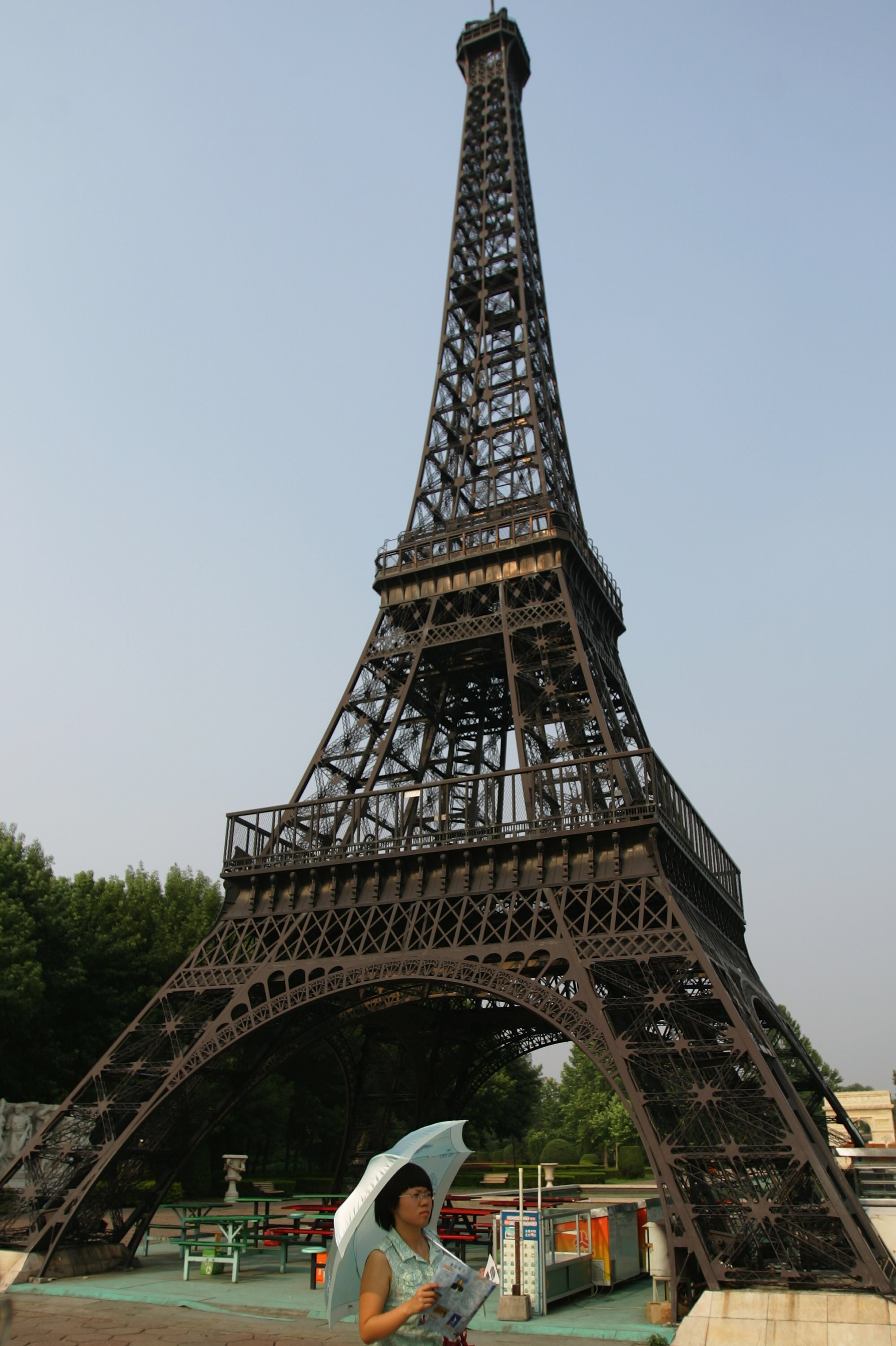 BEIJING - JULY 23:  A Chinese tourist walks under a replica of the Eiffel Tower at the World Park on July 23, 2008 in Beijing, China. The World Park is one of three parks designated for protesters parading during Beijing Olympic Games, according to China