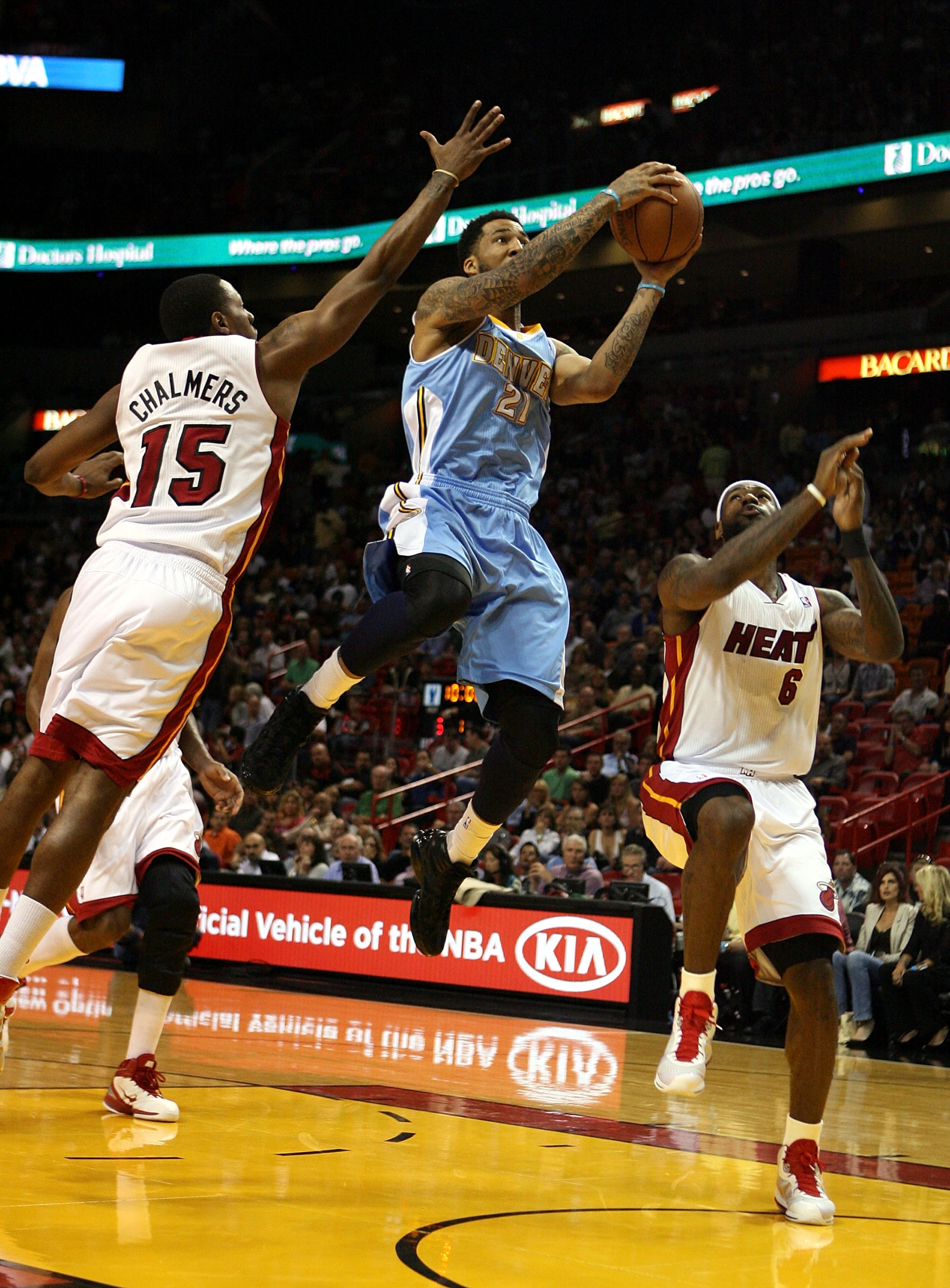 MIAMI, FL - MARCH 19:  Forward Wilson Chandler #21 of the Denver Nuggets (C) drives against Mario Chambers #15 and Dwyane Wade #3 of the Miami Heat at American Airlines Arena on March 19, 2011 in Miami, Florida.  The Heat defeated the Nuggets 103-98. NOTE
