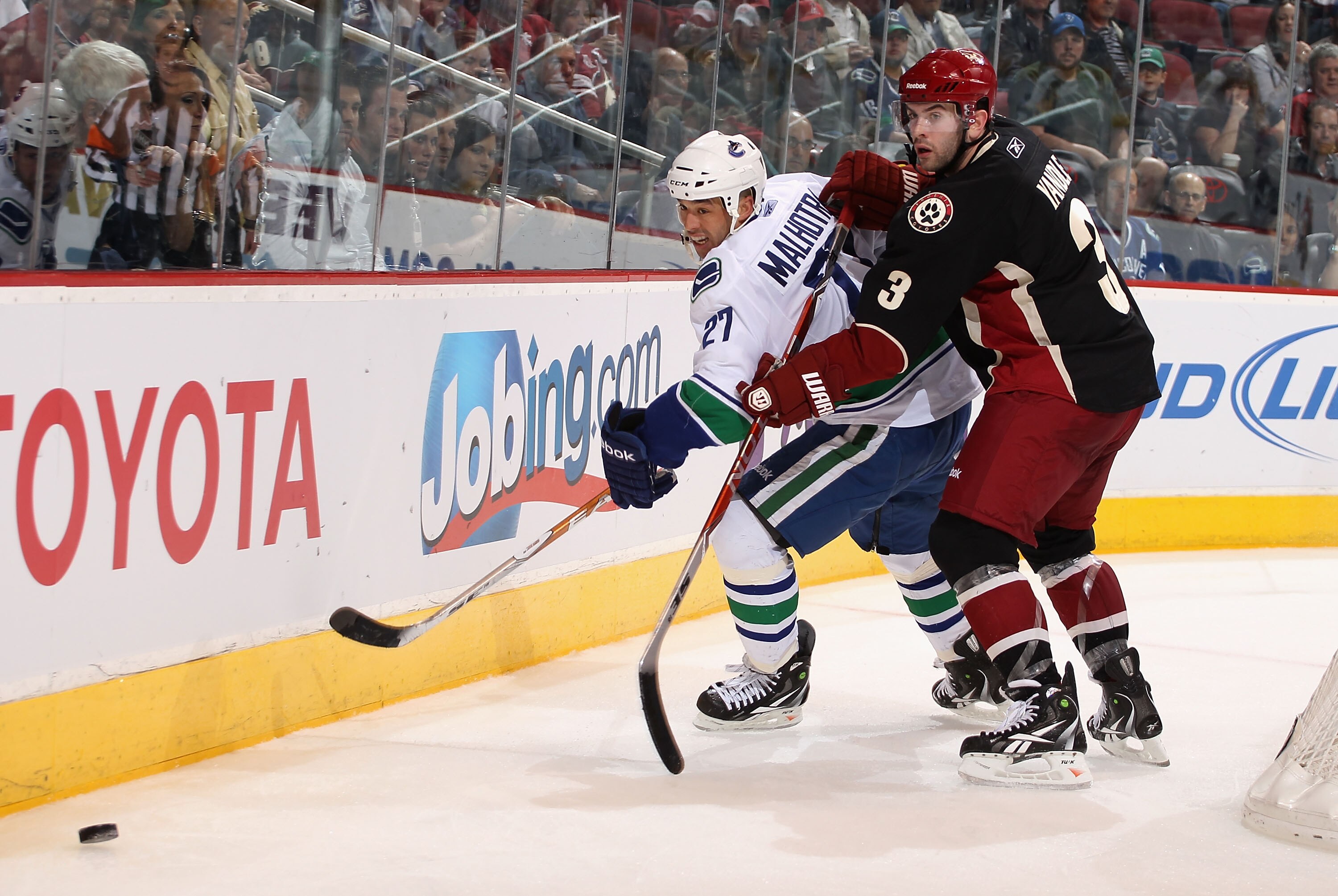 GLENDALE, AZ - MARCH 08:  Manny Malhotra #27 of the Vancouver Canucks skates after the puck with Keith Yandle #3 of the Phoenix Coyotes during the NHL game at Jobing.com Arena on March 8, 2011 in Glendale, Arizona. The Canucks defeated the Coyotes 4-3 in