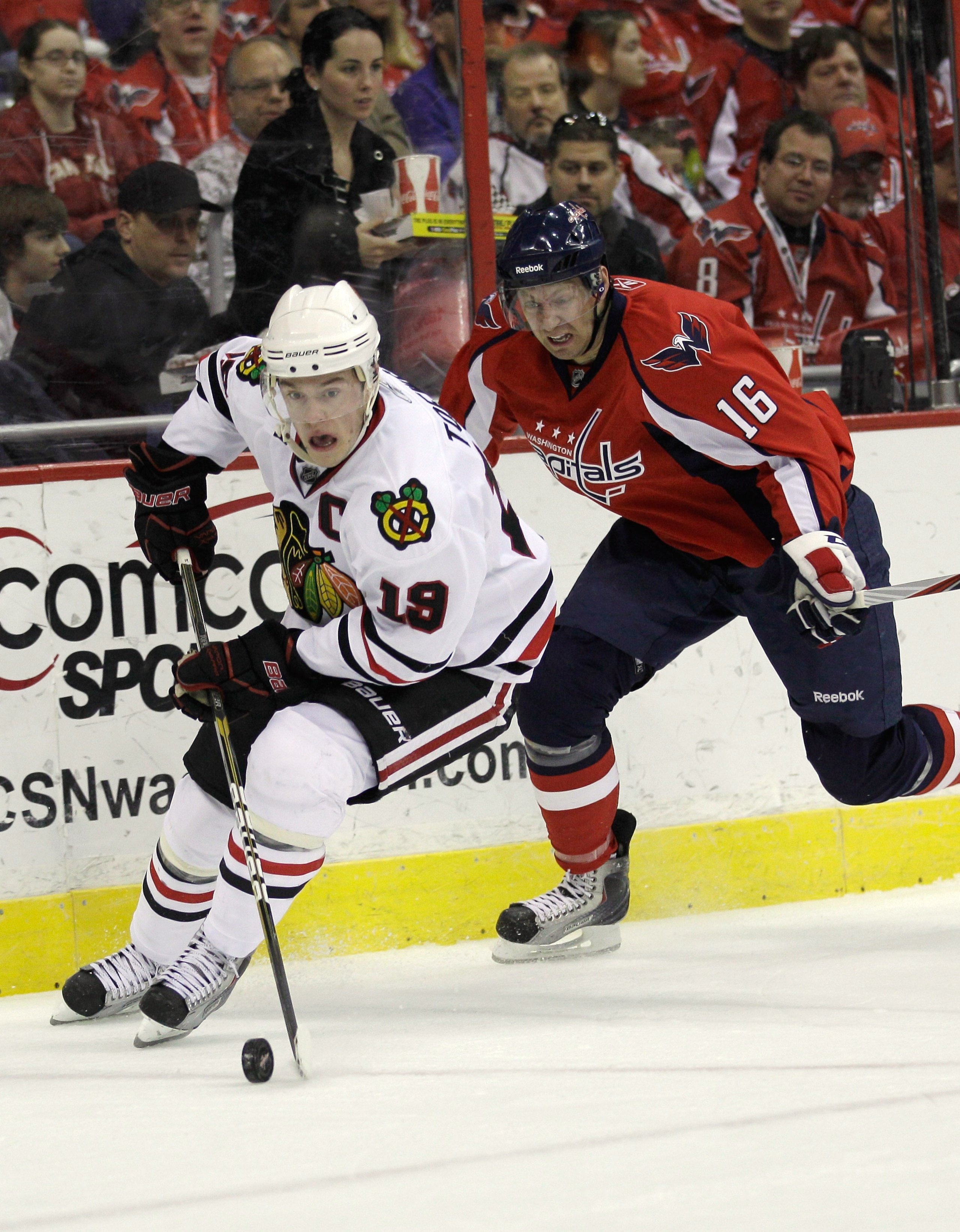 WASHINGTON, DC - MARCH 13: Jonathan Toews #19 of the Chicago Blackhawks moves the puck in front of Eric Fehr #16 of the Washington Capitals at the Verizon Center on March 13, 2011 in Washington, DC.  (Photo by Rob Carr/Getty Images)