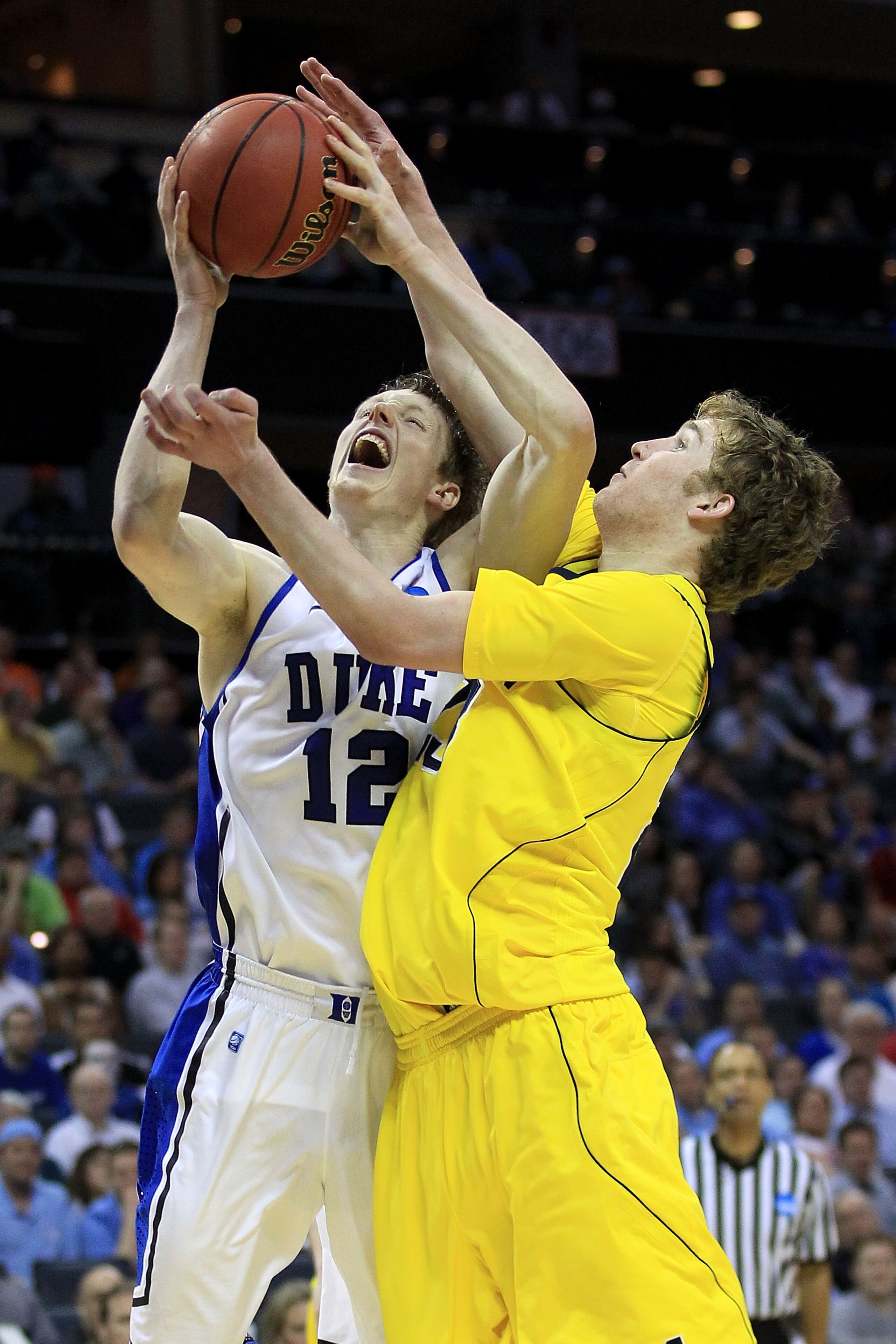 CHARLOTTE, NC - MARCH 20:  Kyle Singler #12 of the Duke Blue Devils goes up for a shot over Evan Smotrycz #23 of the Michigan Wolverines in the second half during the third round of the 2011 NCAA men's basketball tournament at Time Warner Cable Arena on M