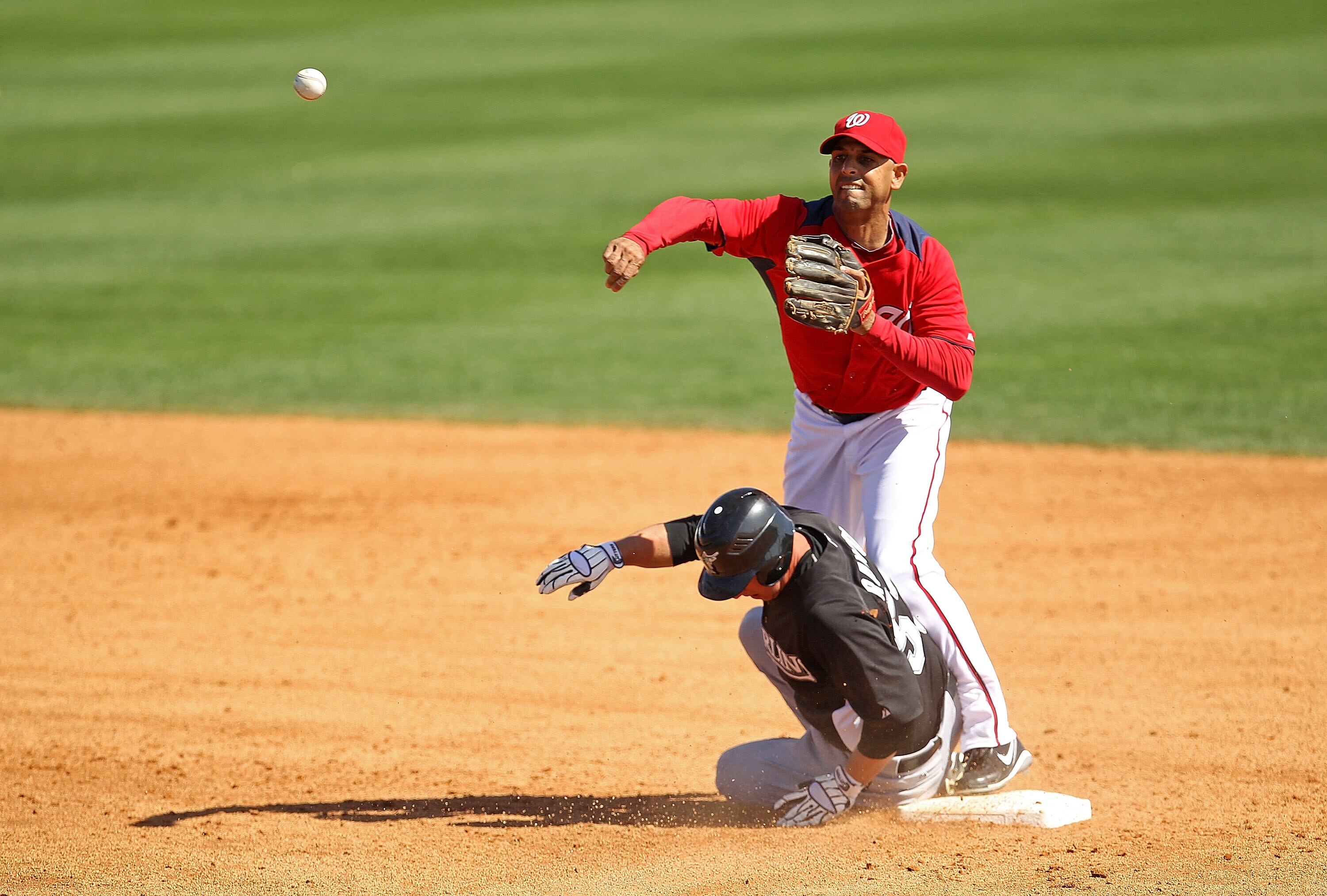 VIERA, FL - MARCH 02:  Alex Cora #13 of the Washington Nationals turns a double play as Frank Mata #57 of the Florida Marlins slides into second during a Spring Training game at Space Coast Stadium on March 2, 2011 in Viera, Florida.  (Photo by Mike Ehrma