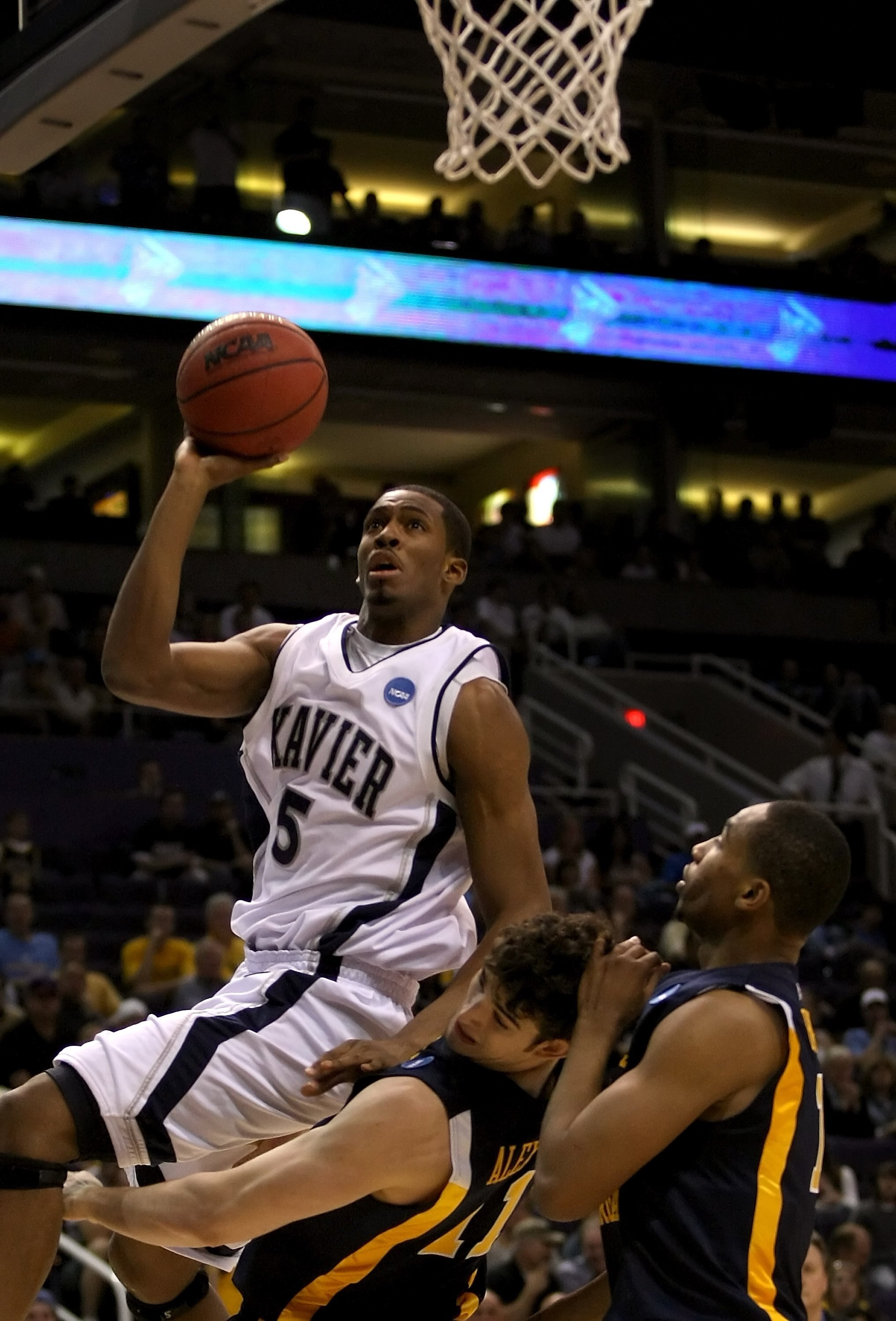 PHOENIX - MARCH 27:  Derrick Brown #5 of the Xavier Musketeers goes up to the basket over Joe Alexander #11 and Da'Sean Butler #1 of West Virginia Mountaineers during the West Regional Sweet 16 game at the U.S. Airways Center on March 27, 2008 in Phoenix,