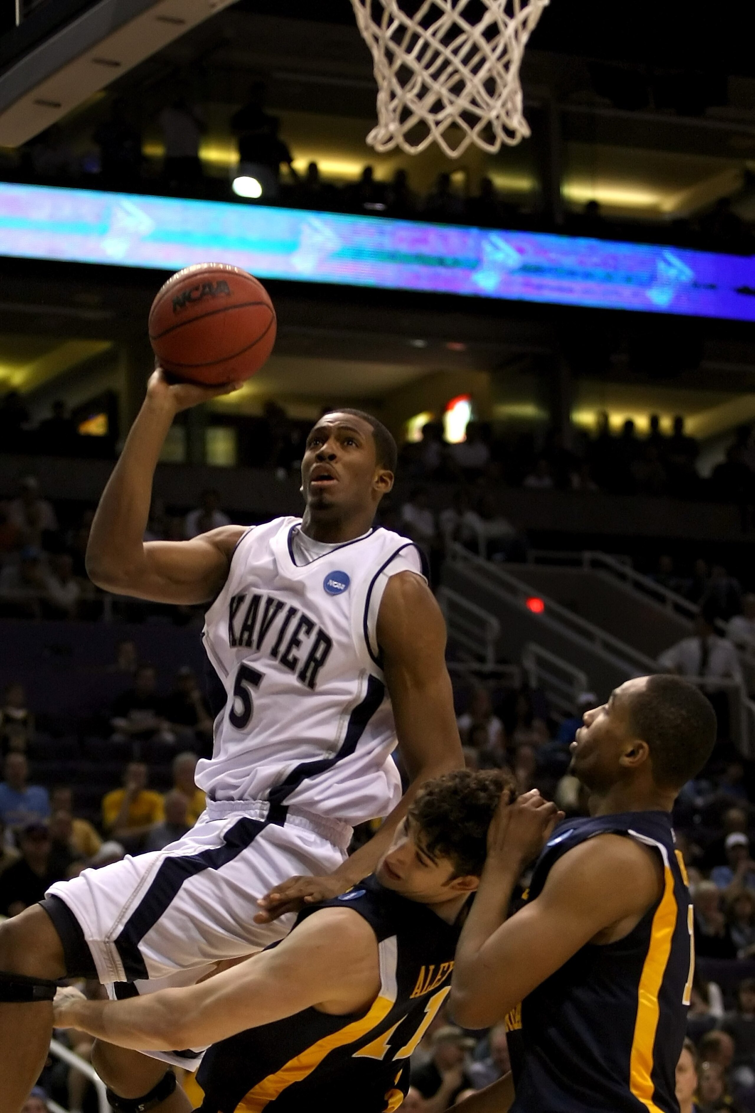 PHOENIX - MARCH 27:  Derrick Brown #5 of the Xavier Musketeers goes up to the basket over Joe Alexander #11 and Da'Sean Butler #1 of West Virginia Mountaineers during the West Regional Sweet 16 game at the U.S. Airways Center on March 27, 2008 in Phoenix,