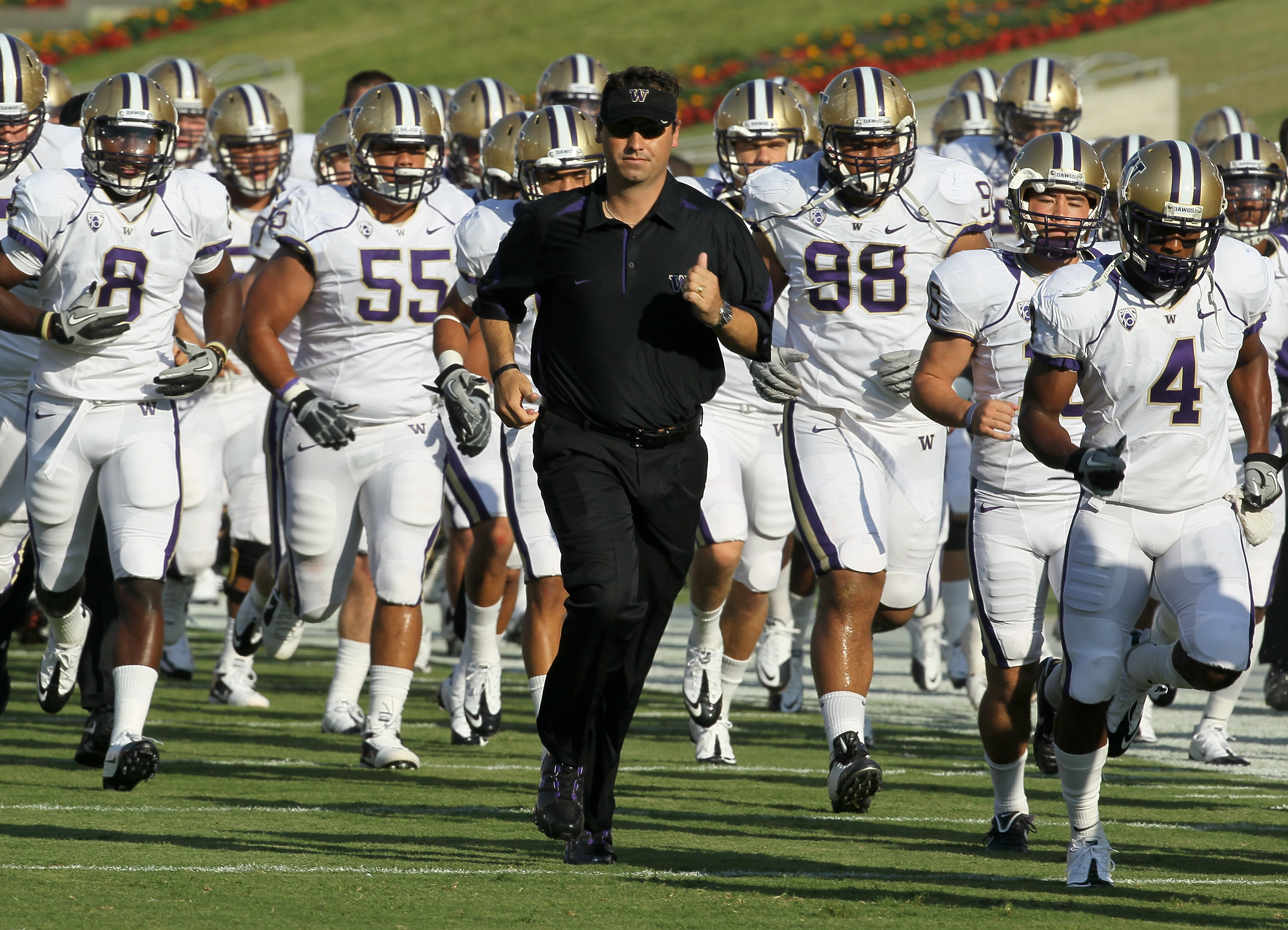 LOS ANGELES - OCTOBER 2:   Head coach Steve Sarkisian of the Washington Huskies runs off the field with his team after warmups for th game with the USC Trojans at the Los Angeles Memorial Coliseum on October 2, 2010 in Los Angeles, California.    (Photo b