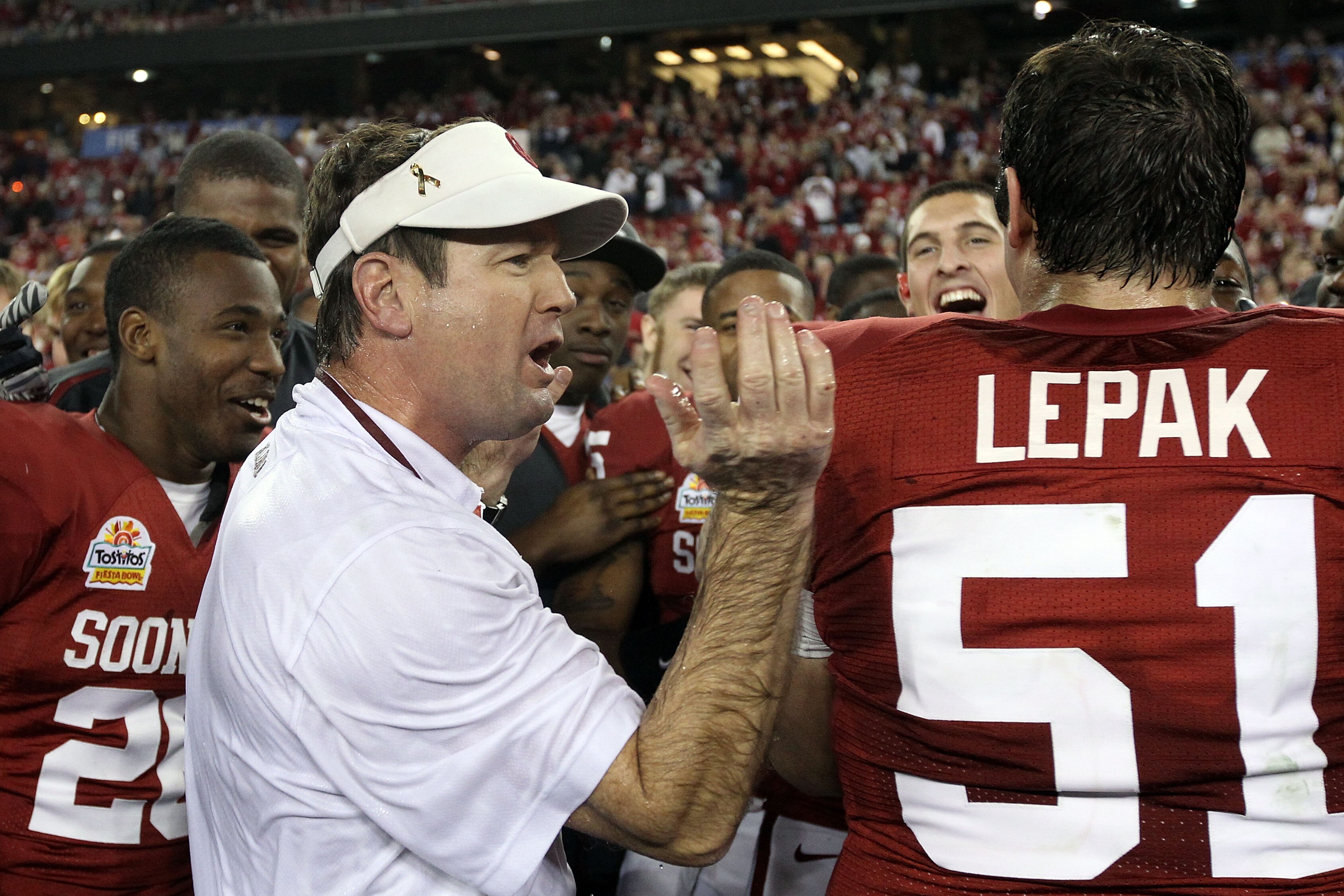 GLENDALE, AZ - JANUARY 01:  Head coach Bob Stoops is hugged by Eric Mensik #69 and Brian Lepak #51 late in the fourth quarter before the Sooners 48-20 victory against the Connecticut Huskies during the Tostitos Fiesta Bowl at the Universtity of Phoenix St